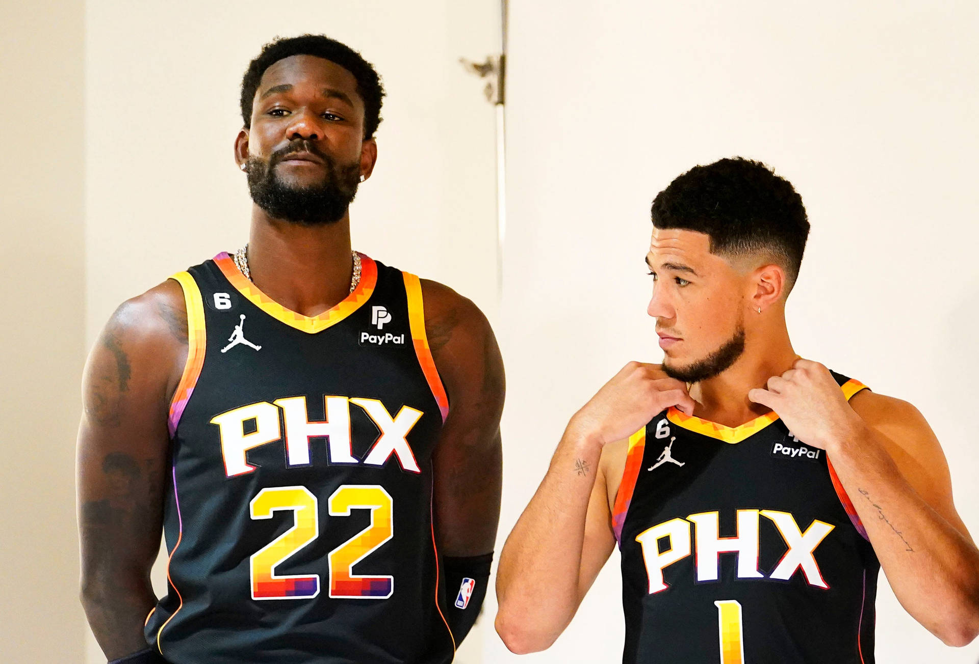 兩位鳳凰城太陽隊籃球運動員身穿隊服在室內擺姿勢。