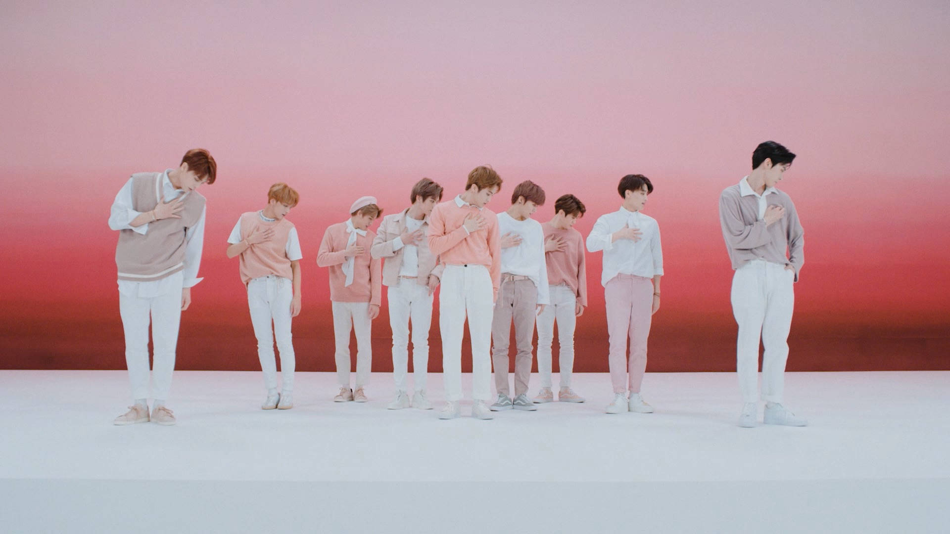NCT 127《Touch》精彩團體鏡頭 壁紙 — 七位身穿粉彩服裝的年輕男性排成一排，背景為粉紅與紅色漸變，雙手放在心口上。