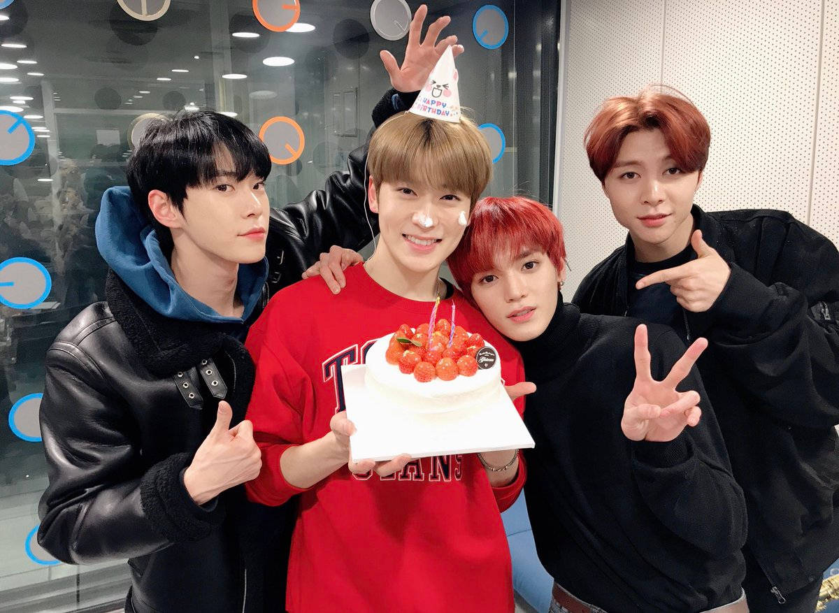 NCT 127 兄弟線慶生照 壁紙 — 四位年輕男士在現代辦公室環境中，用櫻桃蛋糕和派對帽慶祝。