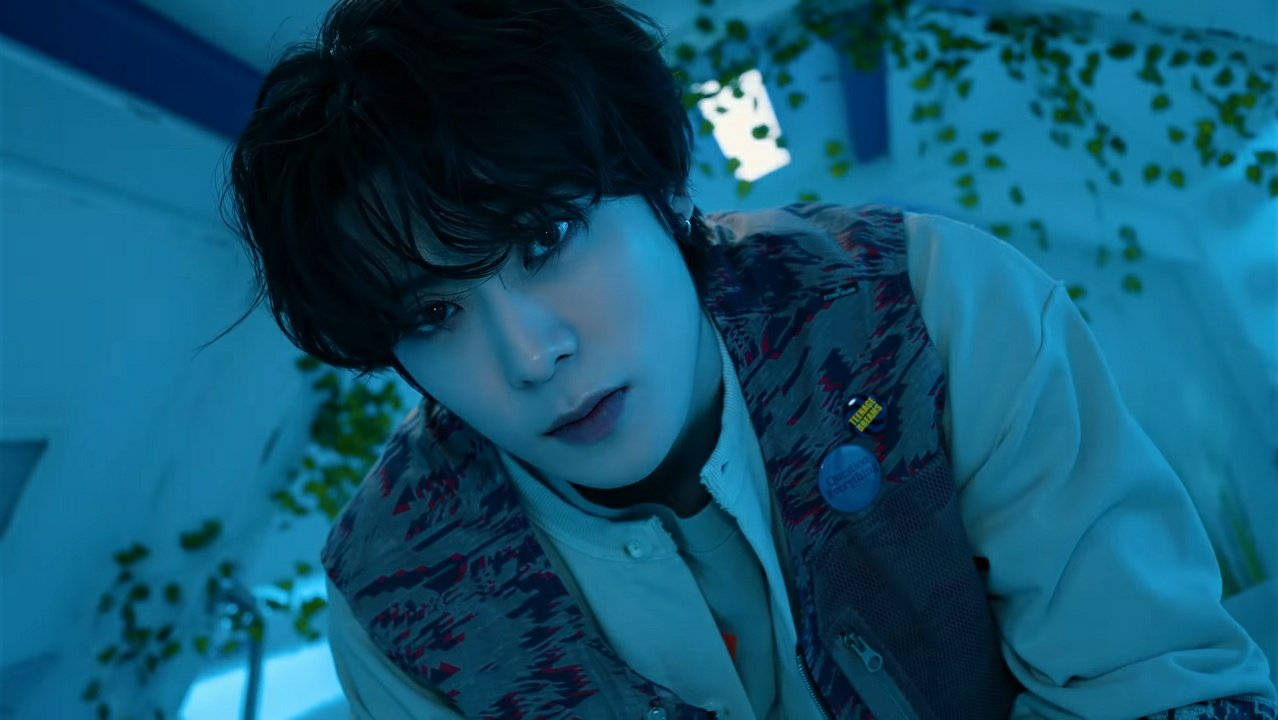 NCT 127 李東赫於Amoeba Culture活動中亮相 壁紙 — 一名深色頭髮的年輕男子在冷藍色燈光下，被綠色藤蔓環繞的場景中專注地凝視。