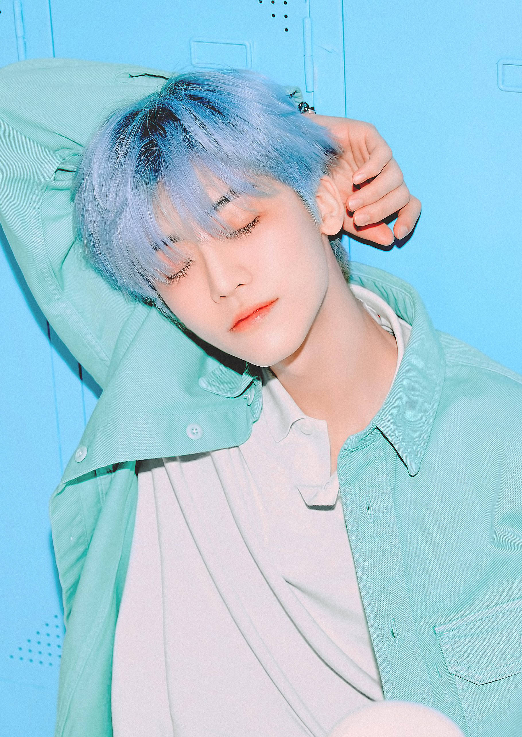 NCT 金廷祐藍髮造型 壁紙 — 一個藍色頭髮的年輕人將頭靠在藍色儲物櫃上，穿著薄荷綠色外套。