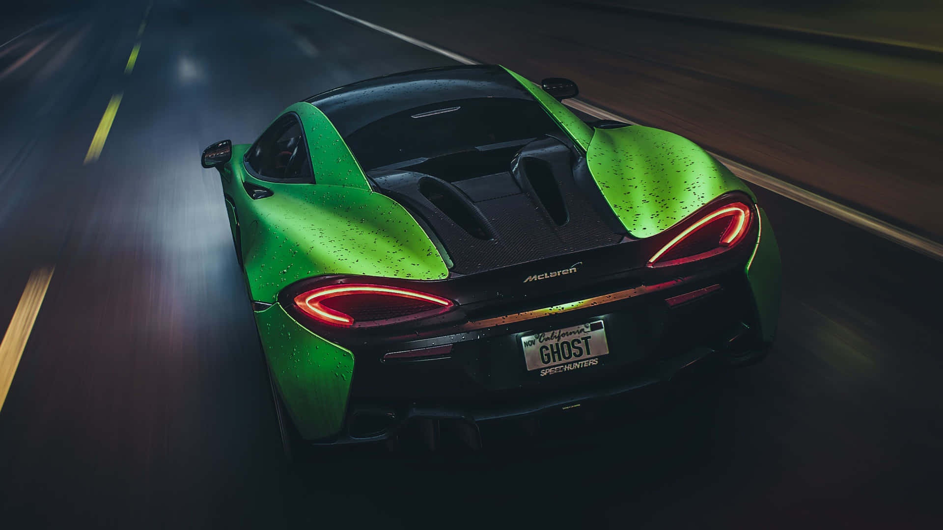 綠色McLaren跑車在夜間潮濕道路上疾馳，尾燈閃爍。