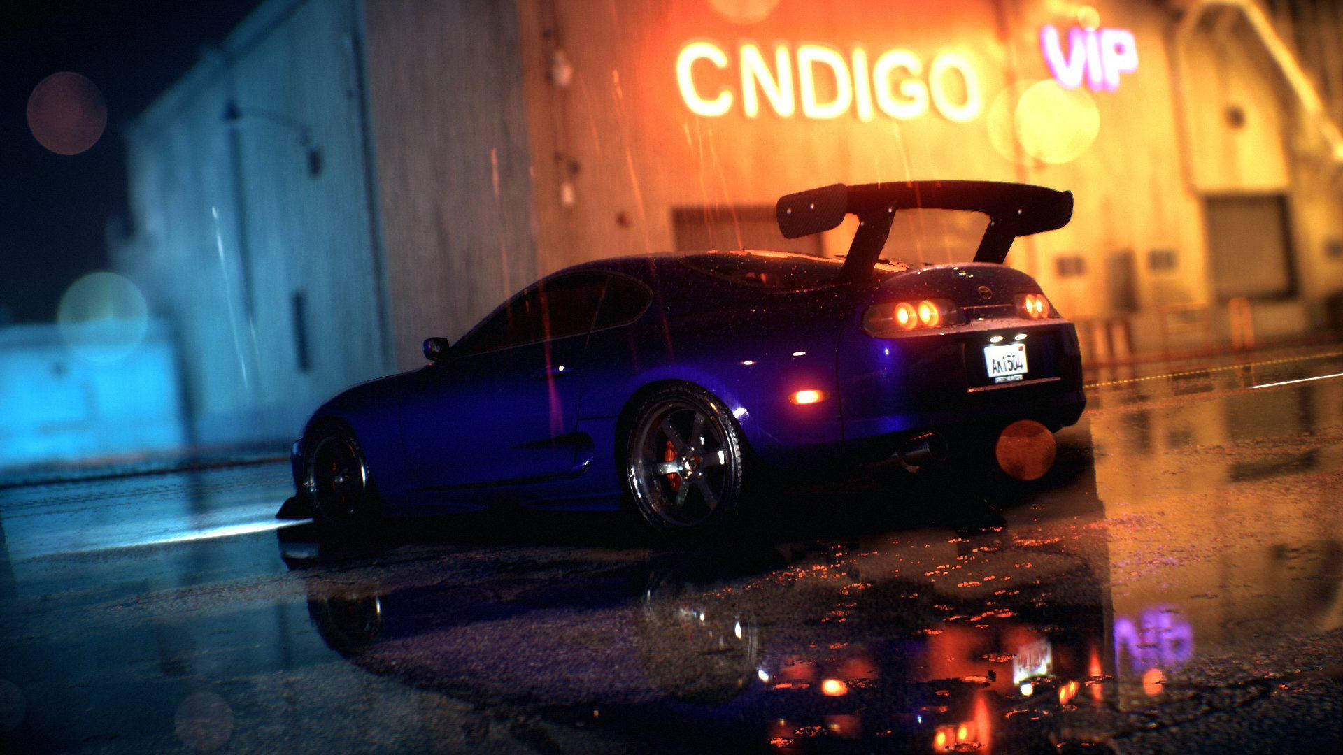 《Need For Speed Heat》奢華超跑飆速追逐 壁紙 — 一輛時尚的藍色跑車帶有大型後擾流板，在閃爍的霓虹燈下，滑過被雨水浸濕的城市街道。