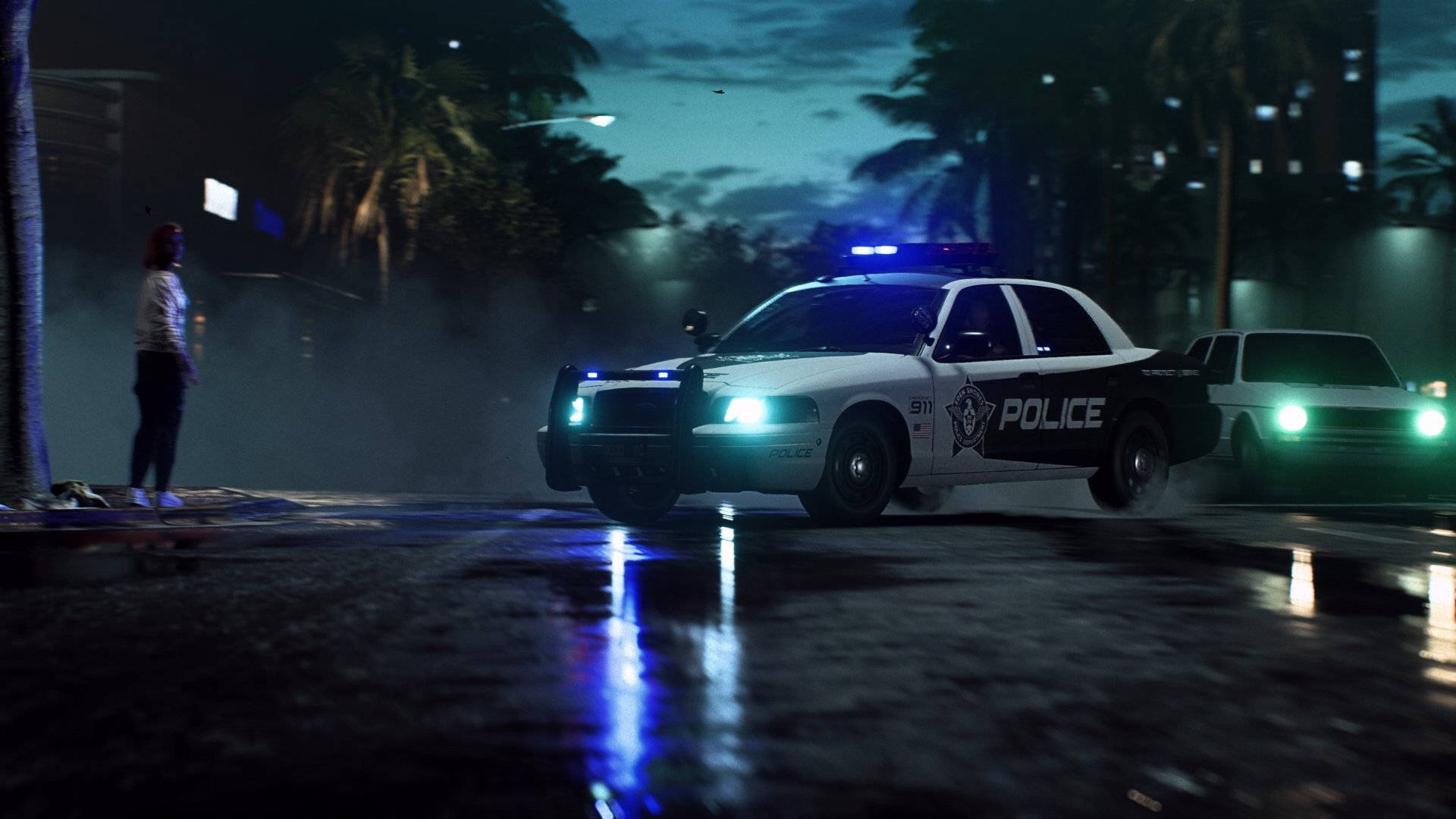 《Need for Speed Heat》警車 壁紙 — 一輛警車閃爍著藍色警燈，在夜間疾馳過濕滑的都市街道，附近站著一個孤獨的身影。