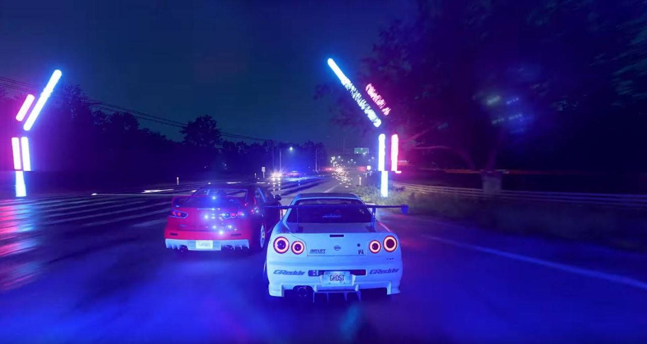 《Need For Speed Heat》夜間賽車 壁紙 — 兩輛跑車在夜間於潮濕的道路上，在發光的霓虹拱門下競速，反射出鮮豔的藍色和粉紅色燈光。