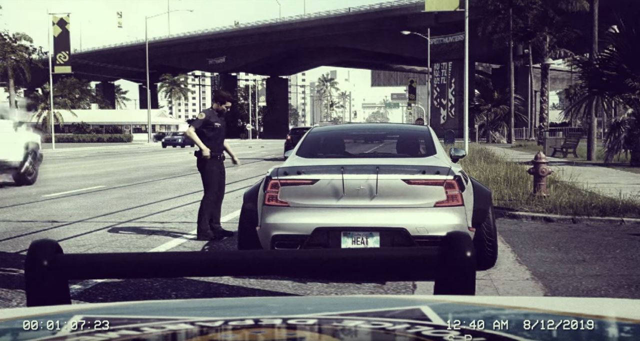 《Need for Speed Heat》夜間街頭賽車 壁紙 — 一名警察站在城市街道上，天橋下的銀色Tesla旁，夜晚有棕櫚樹和交通景象。