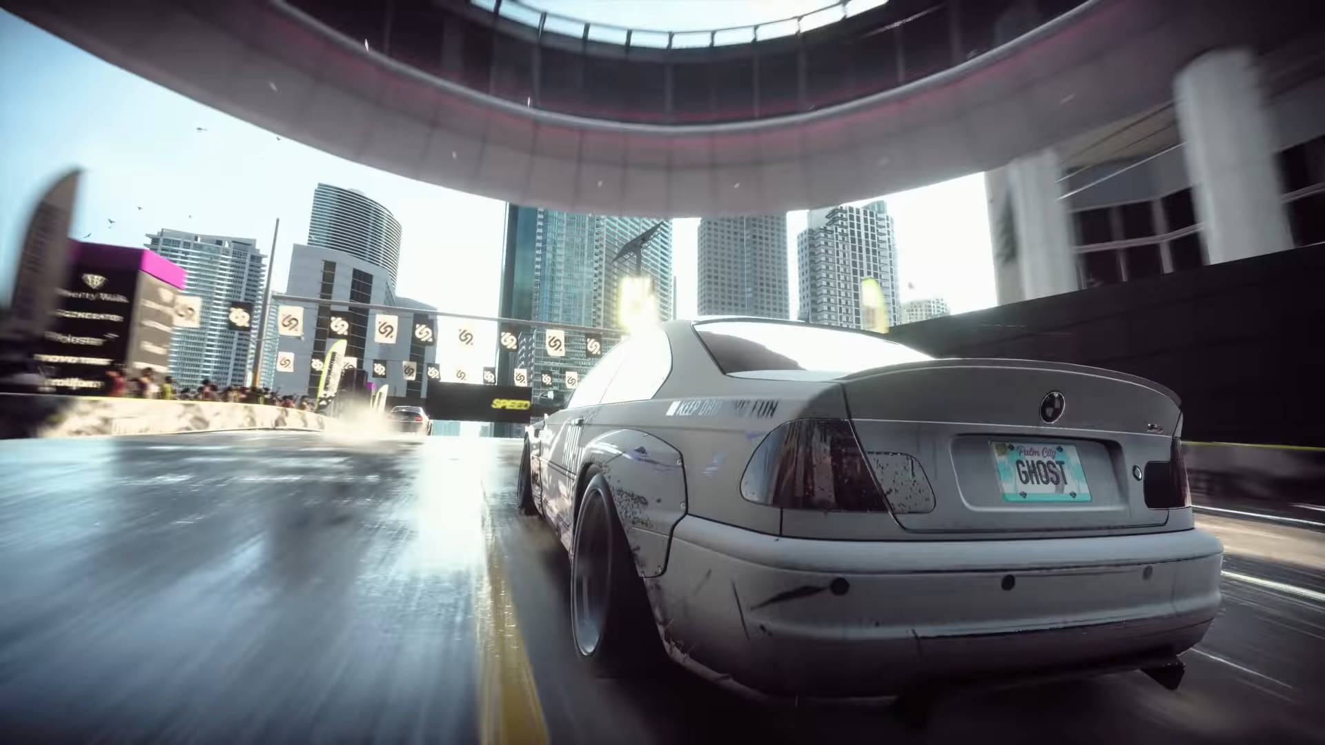 《Need for Speed Heat》高速追捕 壁紙 — 一輛白色寶馬在未來都市賽道上飄移，背景有摩天大樓和發光招牌。