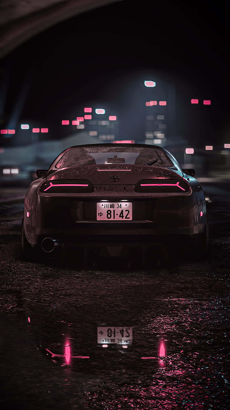 《Need For Speed》中的高能追逐 壁紙 — 一輛時尚的黑色跑車帶有發光的粉紅色尾燈，在夜晚行駛於下雨的隧道中，遠處的城市燈光模糊不清。