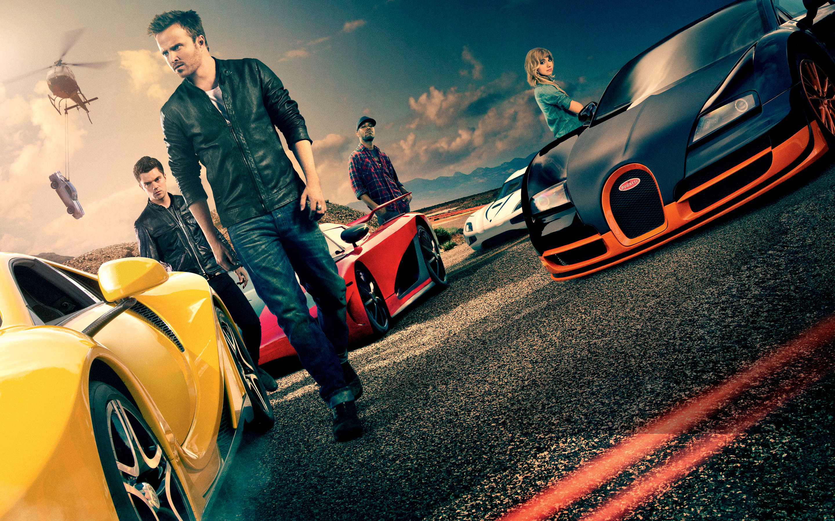 《Need For Speed》海報演員陣容 壁紙 — 穿著皮褸的男人站在沙漠公路上，旁邊是色彩鮮豔的超級跑車，一架直升機在頭頂盤旋。