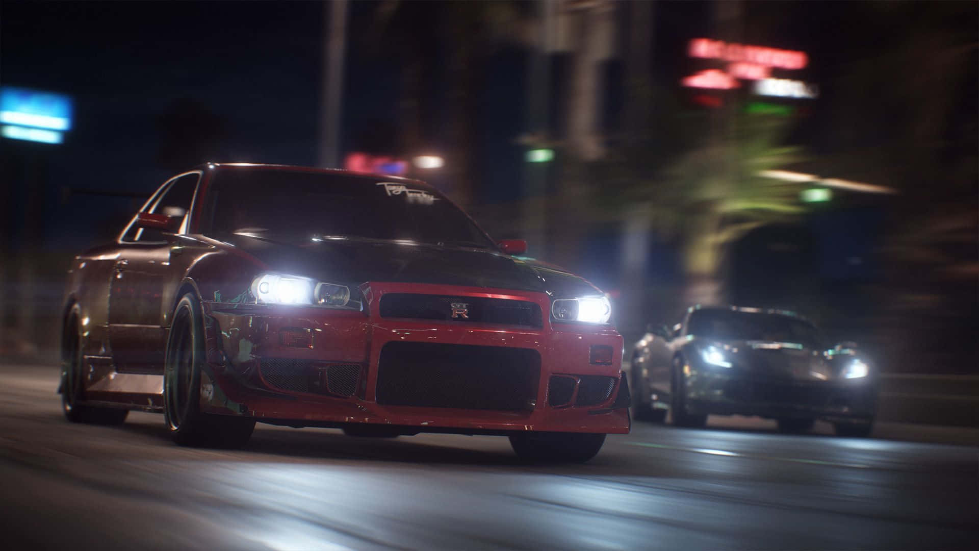 《Need For Speed》背景：R34 Skyline GT-R 壁紙 — 一輛紅色跑車在夜晚霓虹燈閃爍的城市街道上疾馳，車頭燈明亮，留下動態模糊的軌跡。