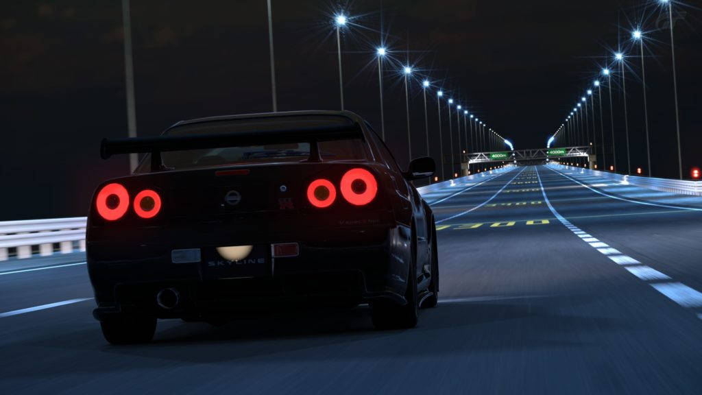 《Need For Speed》黑色日產Skyline GT-R R34 壁紙 — 一輛黑色日產Skyline R34在夜間沿著明亮的高速公路飛馳，帶有發光的紅色圓形尾燈。