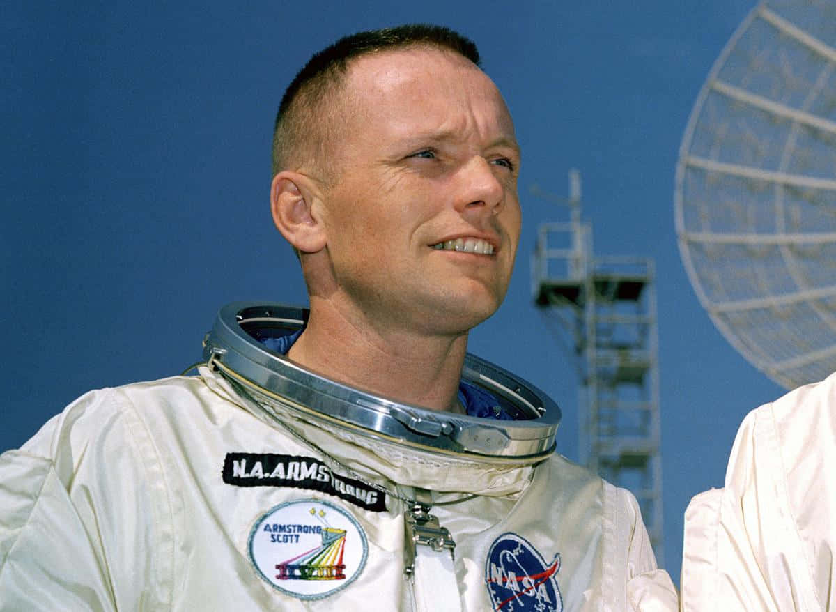 Neil Armstrong 桌布 壁紙 — 太空人尼爾·岩士唐身穿白色NASA太空衣，在晴朗藍天下微笑，背景有衛星天線。