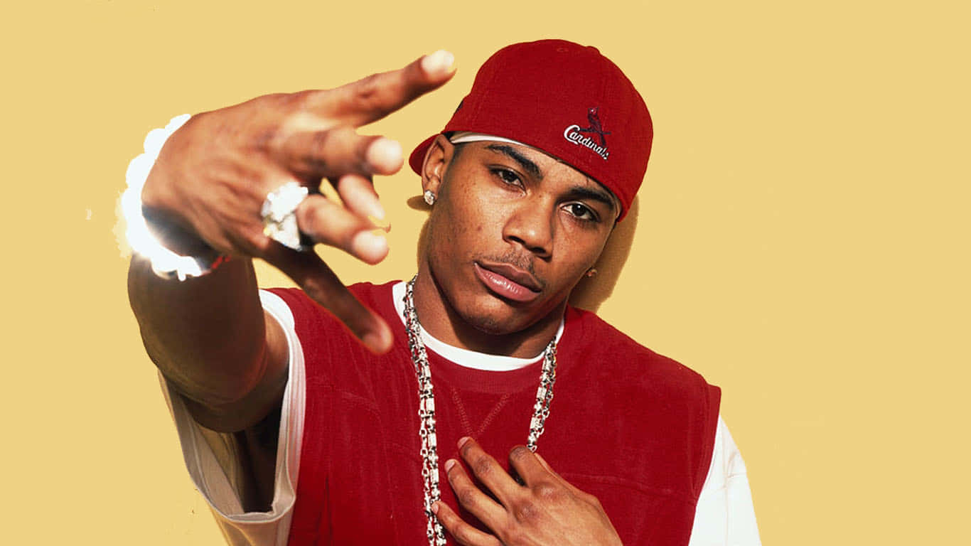 Nelly 巡迴演出現場 壁紙 — 一個自信的男人戴著紅色帽子和背心，在純黃色背景上直接指向觀眾。