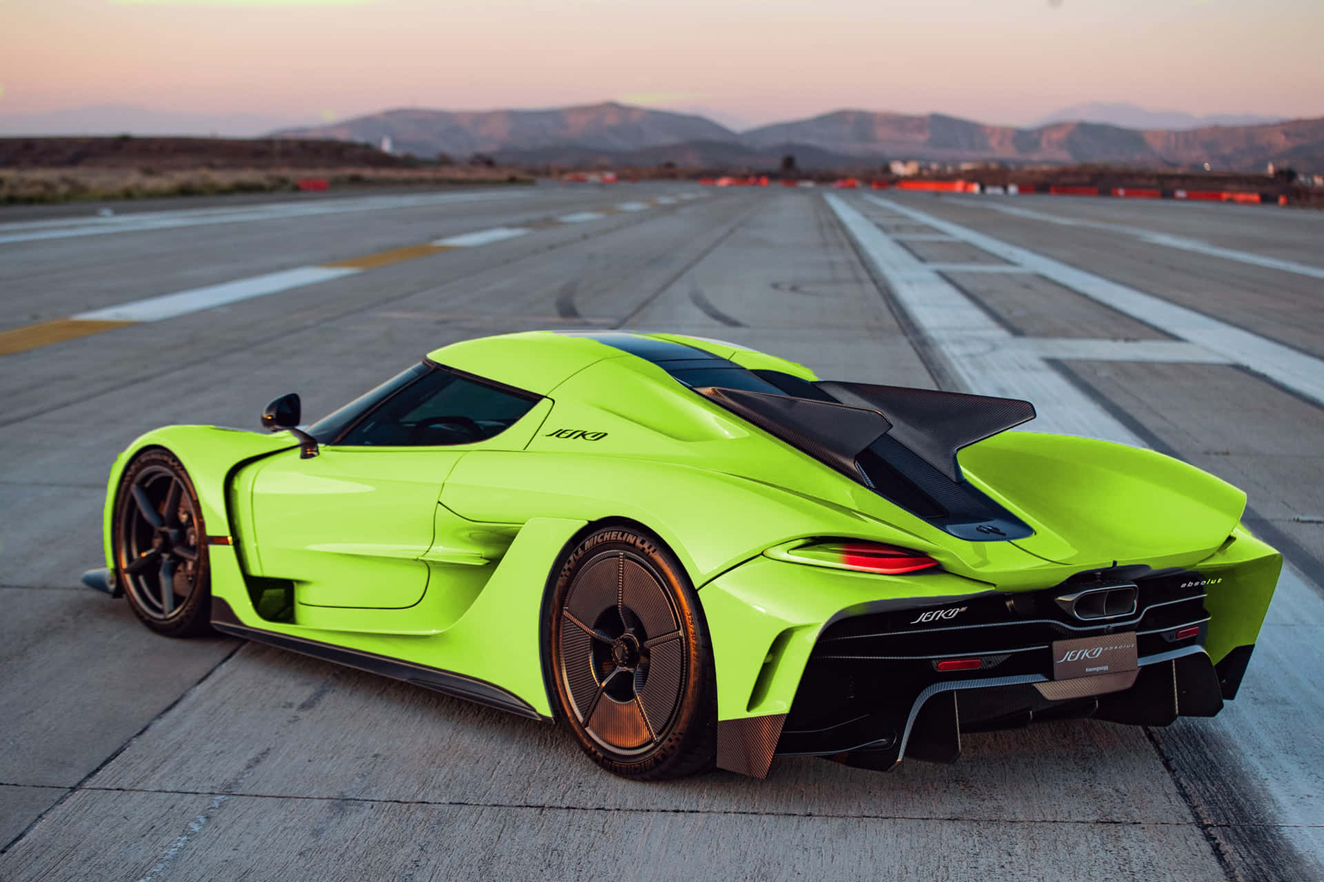  壁紙 — 一架螢光綠色Koenigsegg Jesko hypercar停泊在空曠的跑道上，日落時分，遠山如黛。
