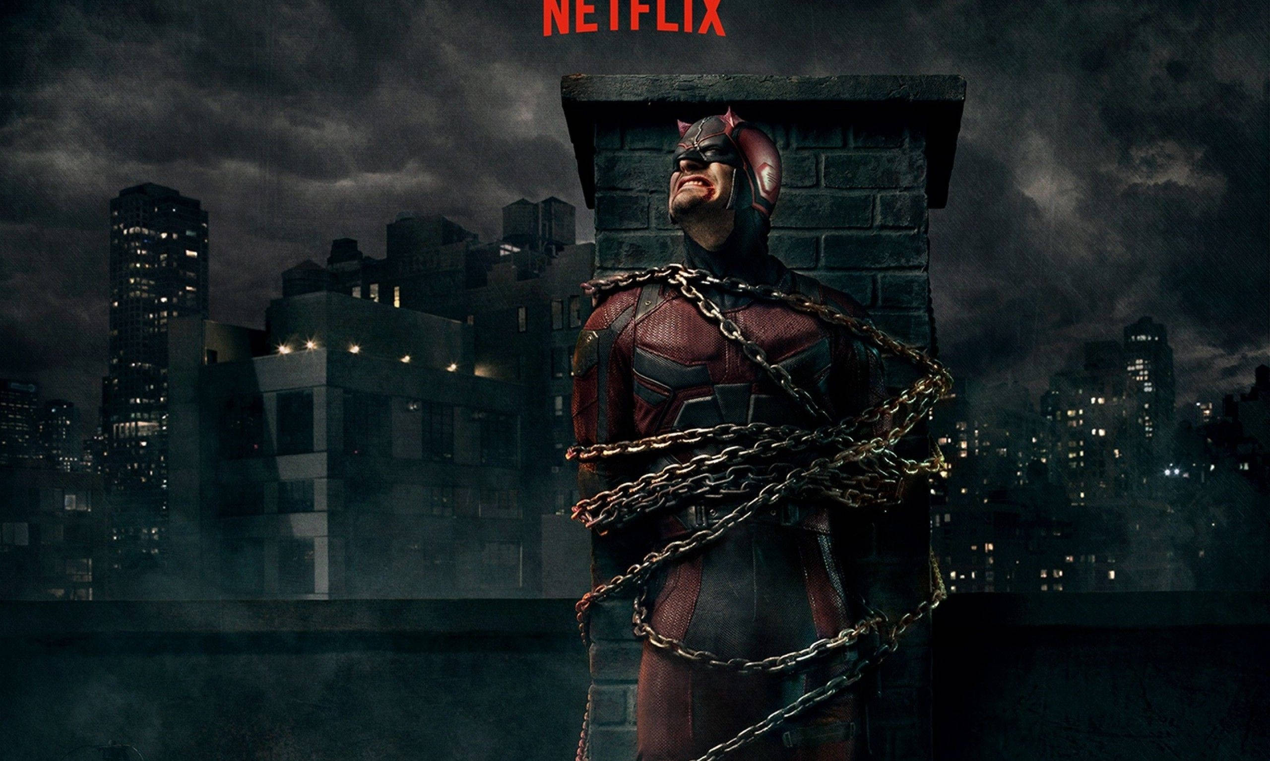 Netflix家庭電影時光 壁紙 — 夜間，夜魔俠被鎖鏈綁在屋頂上，背景是暴風雨的城市天際線。