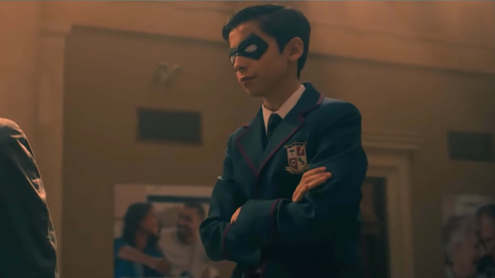 一個戴著口罩的男學生在走廊裡交叉雙臂站立。