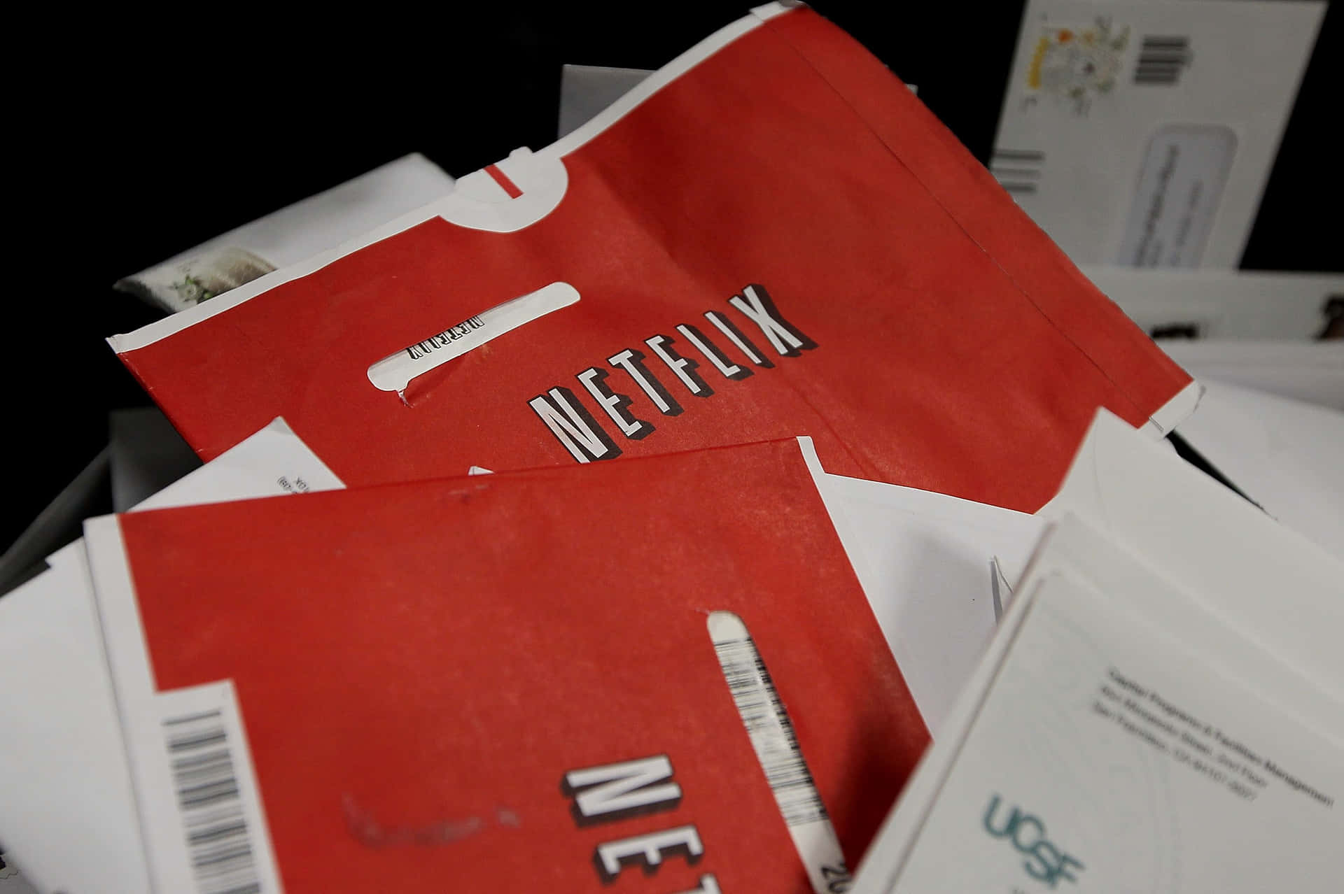 一堆紅色Netflix郵件和白色信封在黑暗的堆中。
