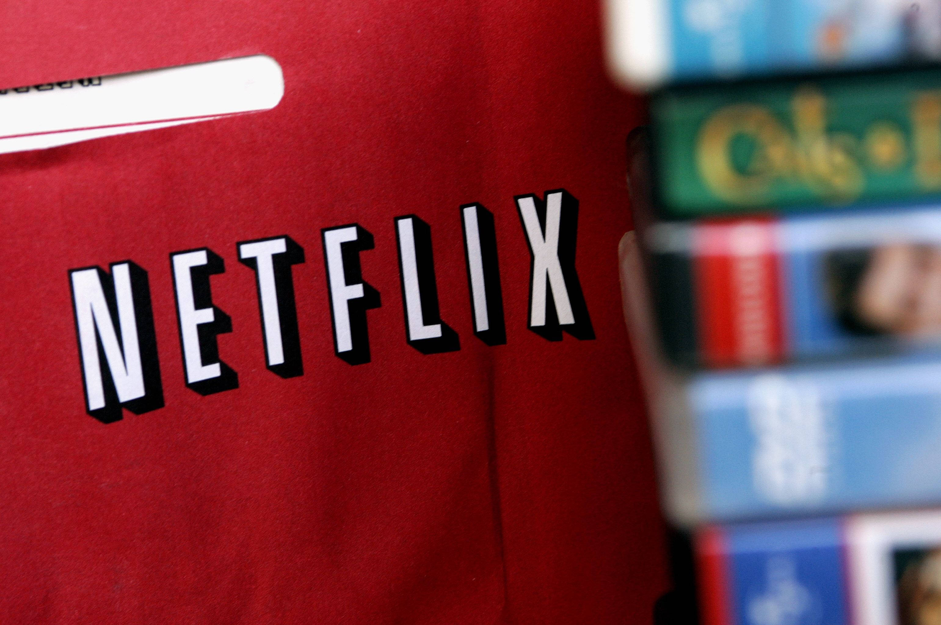 Netflix紅色商品 壁紙 — 一個紅色Netflix袋的特寫，背景有一疊模糊的VHS錄影帶。