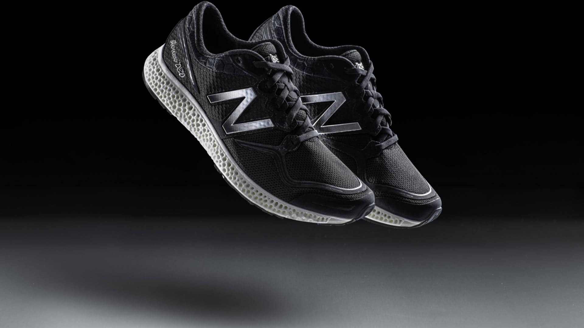 New Balance 三維鞋底 壁紙 — 一對帶有銀色標誌的黑色 New Balance 運動鞋在深色漸變背景上漂浮。