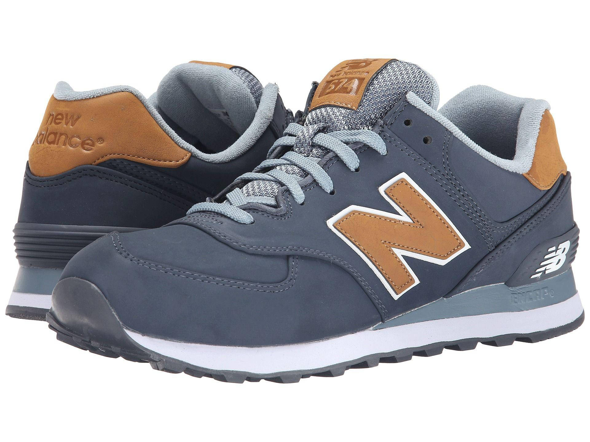 New Balance 深灰卡其色調 壁紙 — 一對海軍藍色New Balance運動鞋，帶有棕褐色點綴和白色鞋底，展示在潔白背景上。