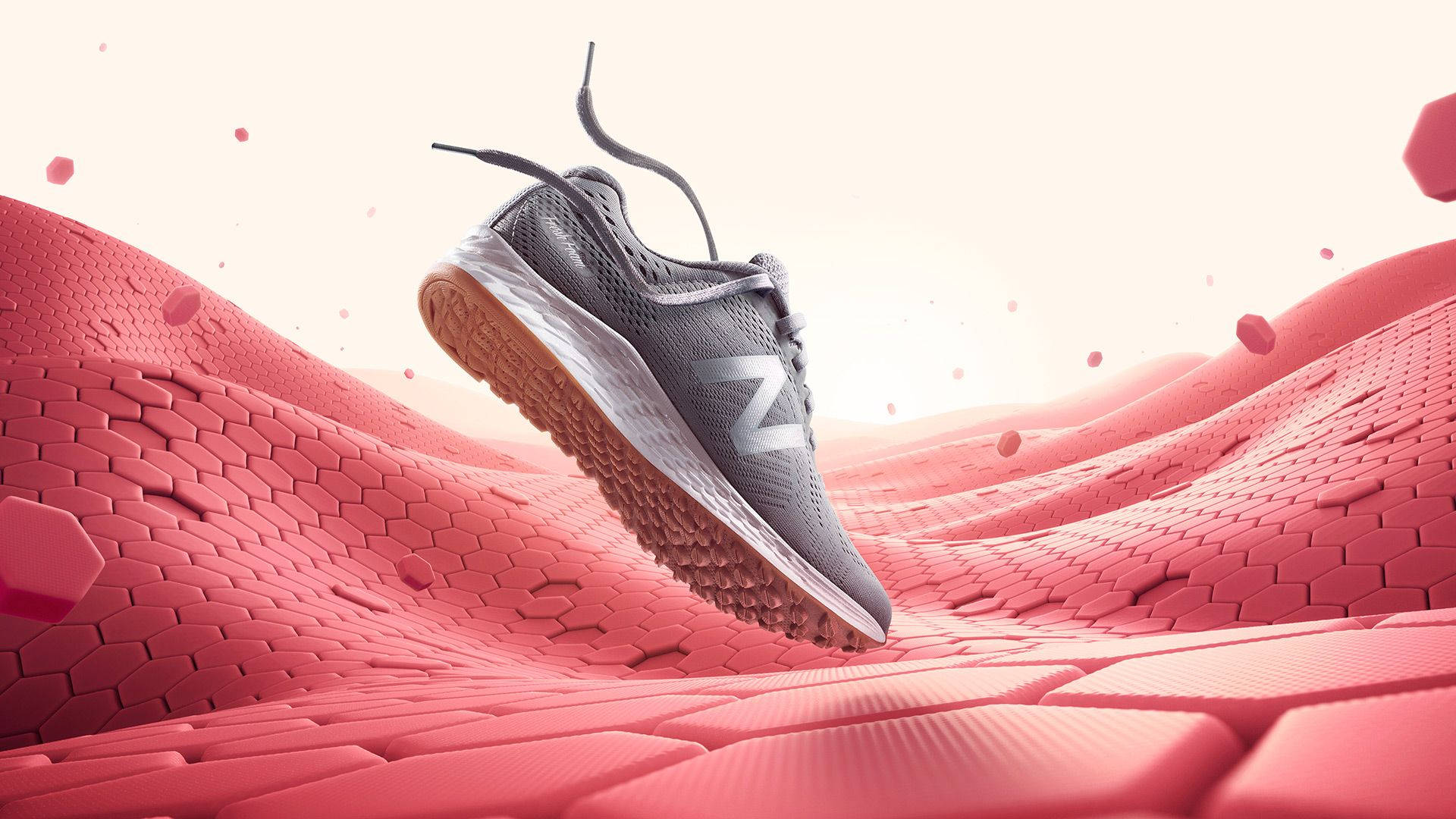 New Balance 跑步鞋 壁紙 — 一隻灰色跑鞋懸浮在帶有浮游粒子的紋理粉紅色六邊形景觀上方。