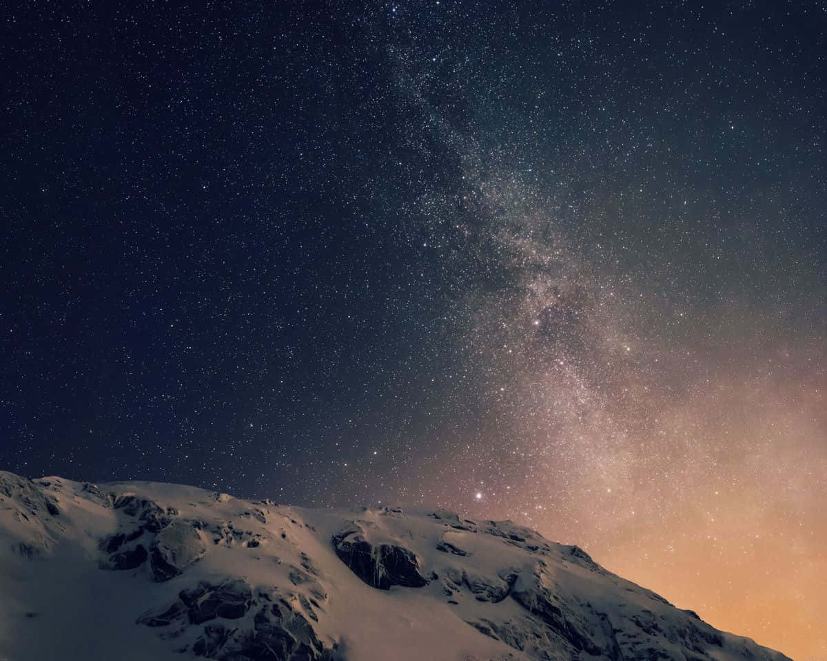 Nexus 6 星空壁紙 壁紙 — 白雪覆蓋的山脊，在令人嘆為觀止的星空下，銀河以溫暖的色調閃耀。
