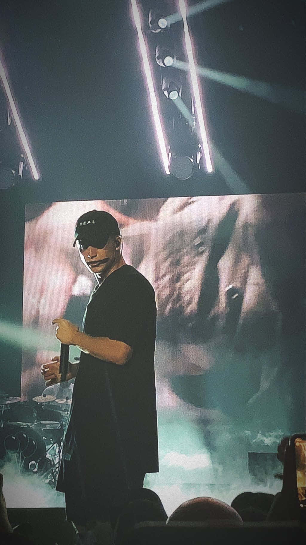 一位音樂家在明亮的燈光下，身後有一個大屏幕，在舞台上表演。