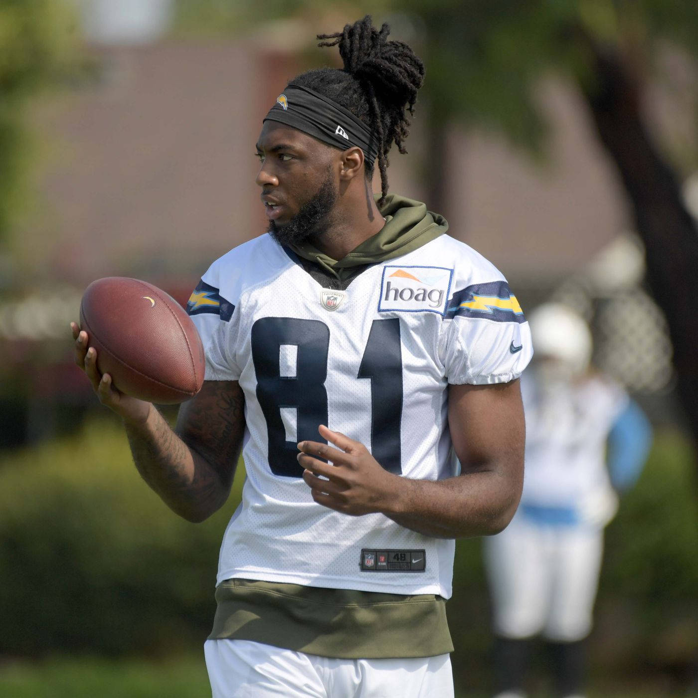 邁克·威廉斯 NFL 訓練營 壁紙 — 一位專注的美式足球員身穿白色球衣，號碼81，在陽光明媚的日子裡戶外拿著一個棕色美式足球。
