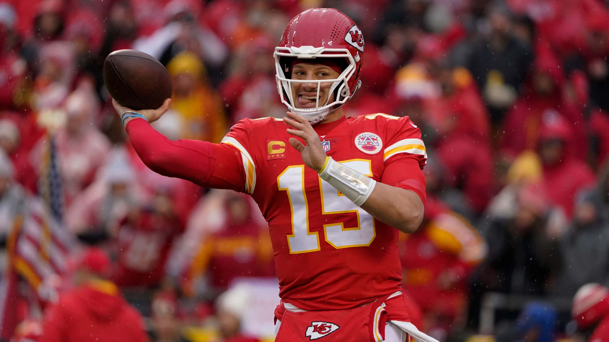 NFL季後賽接球圖片 壁紙 — 一名身穿紅色球衣、背號15號的美式足球四分衛在雨中比賽中投球，背景有球迷。