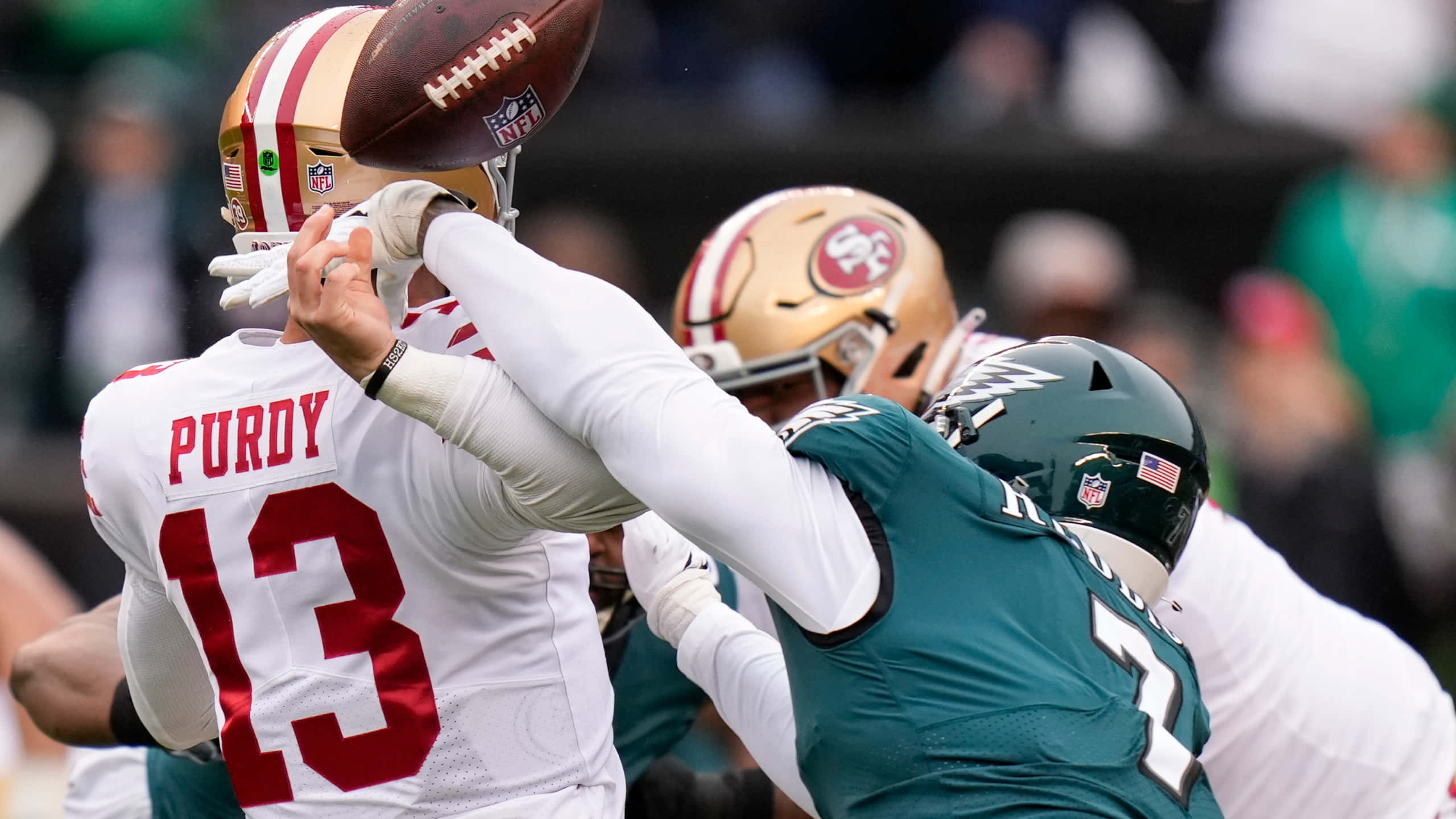 哈桑·雷迪克 NFL 外線衛 壁紙 — 三藩市49人隊的四分衛被費城老鷹隊的防守球員擒殺，同時美式足球在空中飛過。