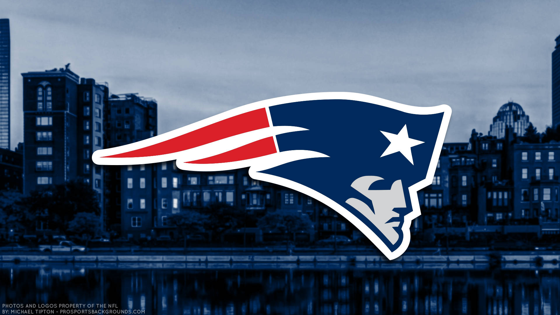 新英格蘭愛國者隊 NFL 壁紙 — 新英格蘭愛國者隊標誌突出顯示在黃昏時分的城市天際線上，帶有藍色和紅色點綴。
