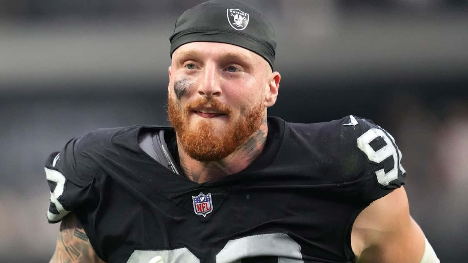 NFL 職業美式足球運動員 Maxx Crosby 壁紙 — 一名留鬍鬚的NFL美式足球員身穿黑色Raiders球衣，號碼92，在比賽中展現決心的特寫。