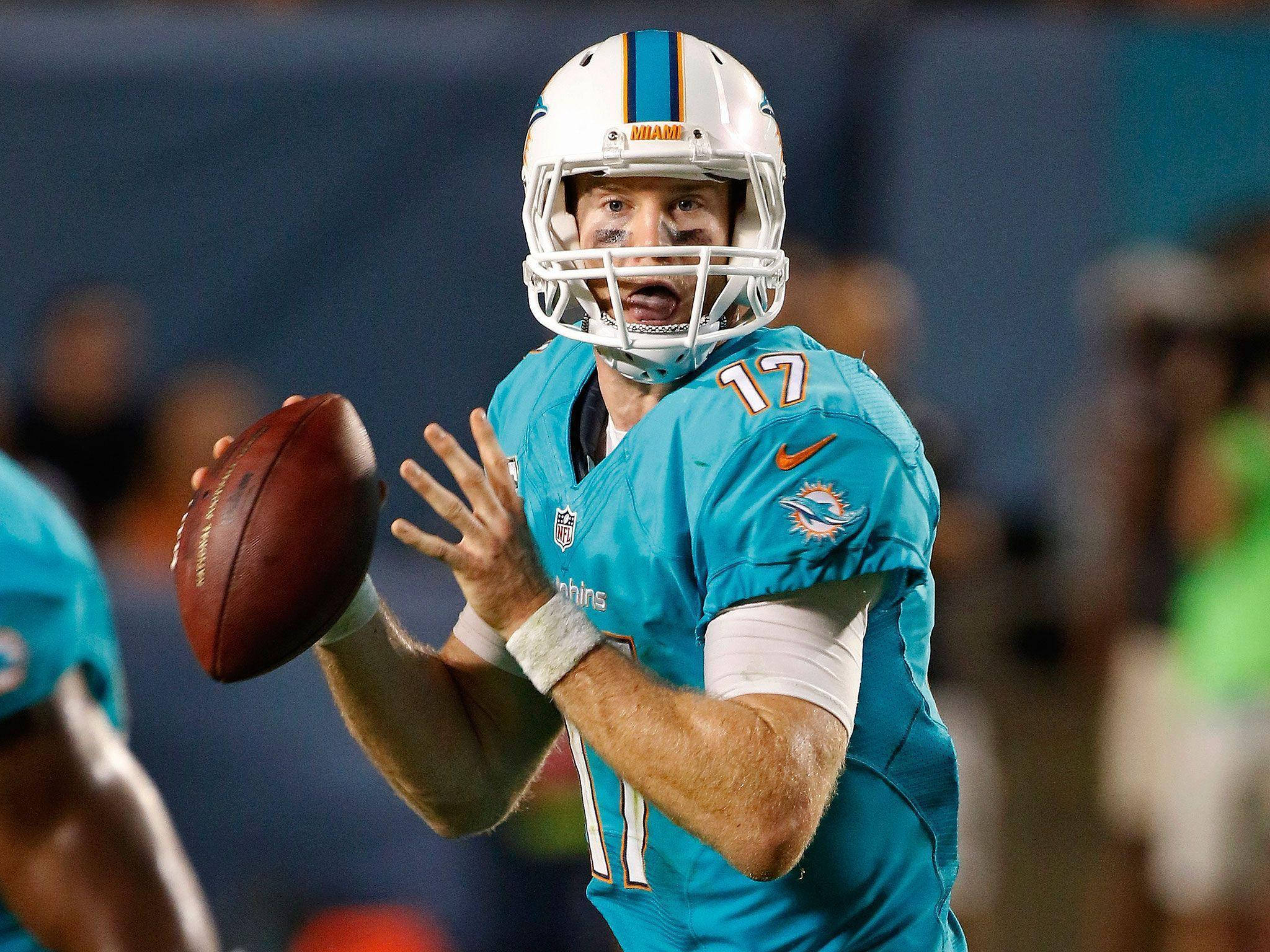 瑞安·坦尼爾NFL比賽隨拍 壁紙 — 一名身穿青綠色球衣的邁阿密海豚四分衛在夜間比賽中，於球場燈光下準備擲出橄欖球。
