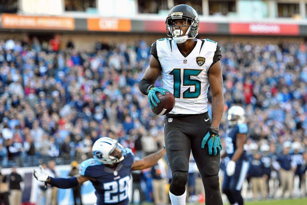 NFL Pro Bowl首選替補艾倫·羅賓遜 壁紙 — 一名身穿白色和青綠色球衣的傑克遜維爾美洲虎隊美式足球員帶球奔跑，而田納西泰坦隊的防守球員在座無虛席的體育場中追趕他。