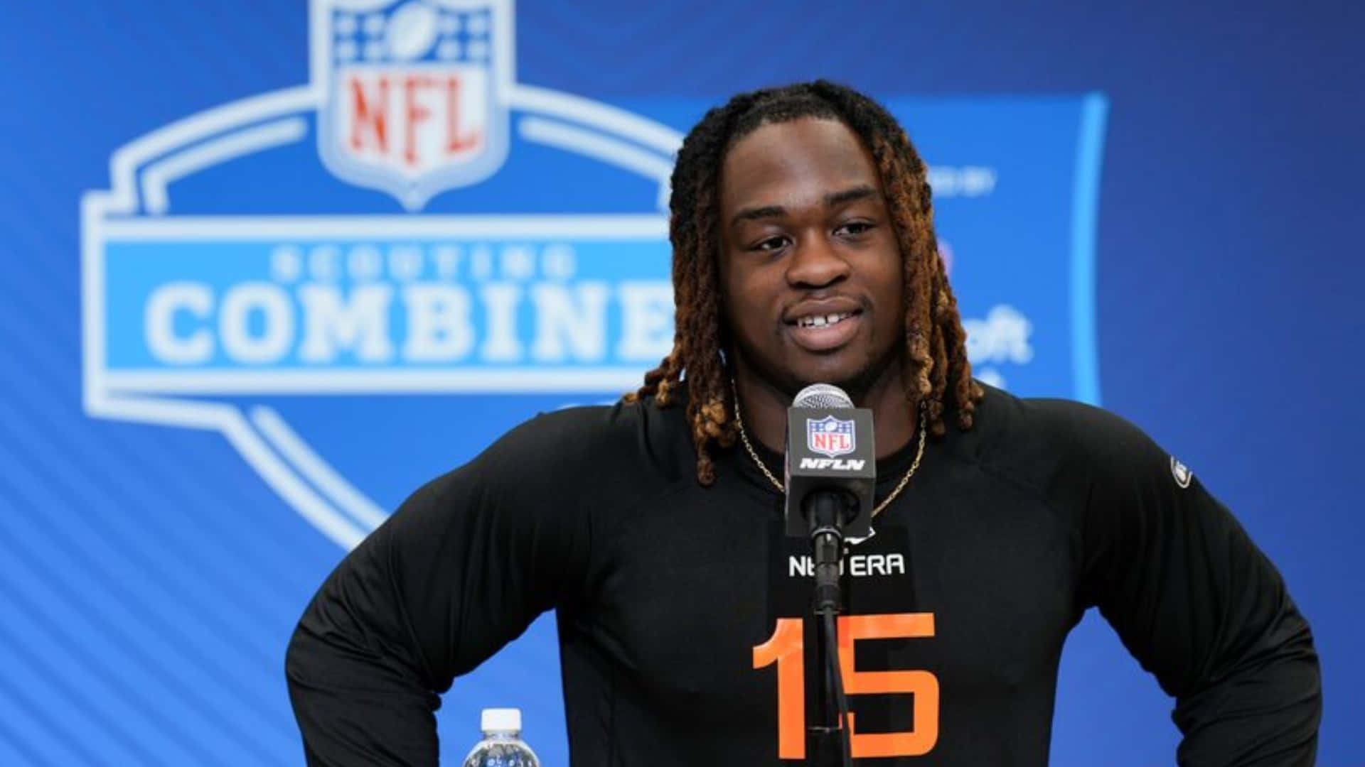  壁紙 — NFL 球員身穿黑色球衣，橙色15號，在Scouting Combine記者會上對著咪高峰發言。