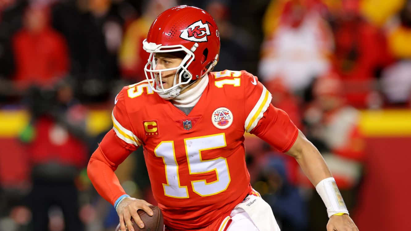 NFL Quarterbacks 桌布 壁紙 — 一位專注的NFL四分衛身穿紅色15號球衣，在夜間比賽中準備擲出橄欖球。