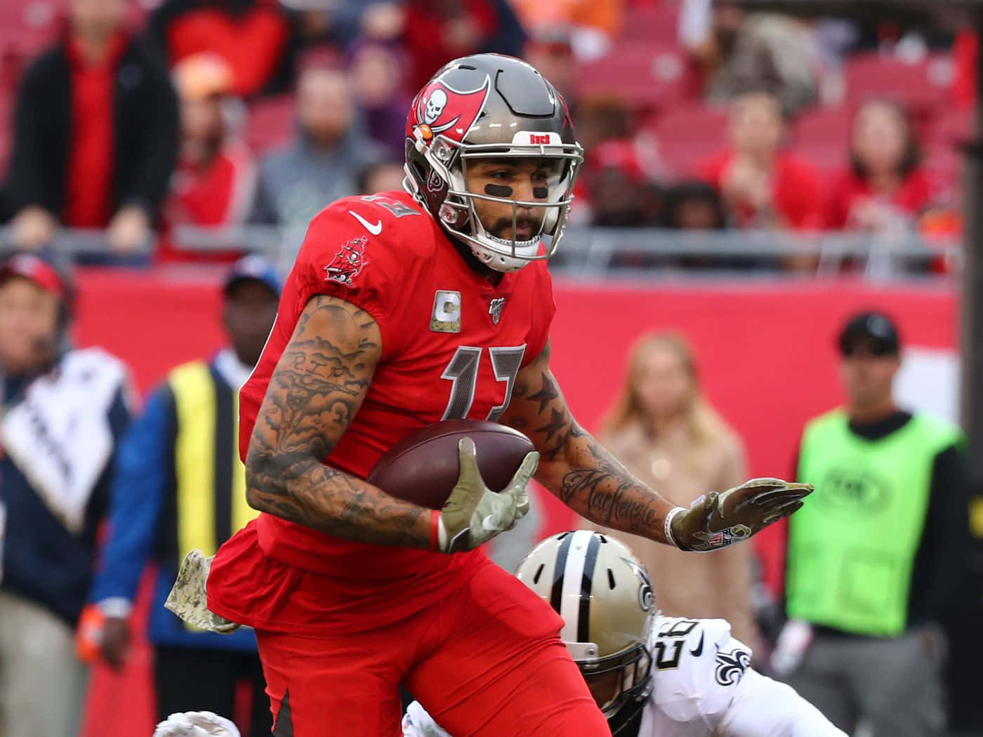 NFL球員邁克·埃文斯於硬石體育場 壁紙 — 一名身穿紅色球衣的坦帕灣海盜隊美式足球員在比賽中持球奔跑，背景有球迷。
