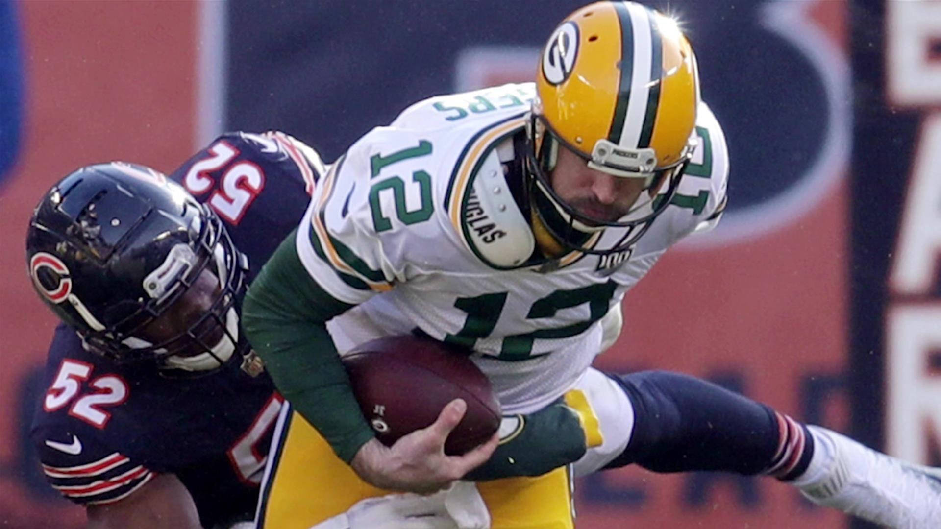 NFL 卡里爾·麥克對陣亞倫·羅傑斯 壁紙 — 綠灣包裝工四分衛亞倫·羅傑斯在芝加哥熊隊線衛的擒抱下向右跑動，這是一場高風險的NFL比賽。