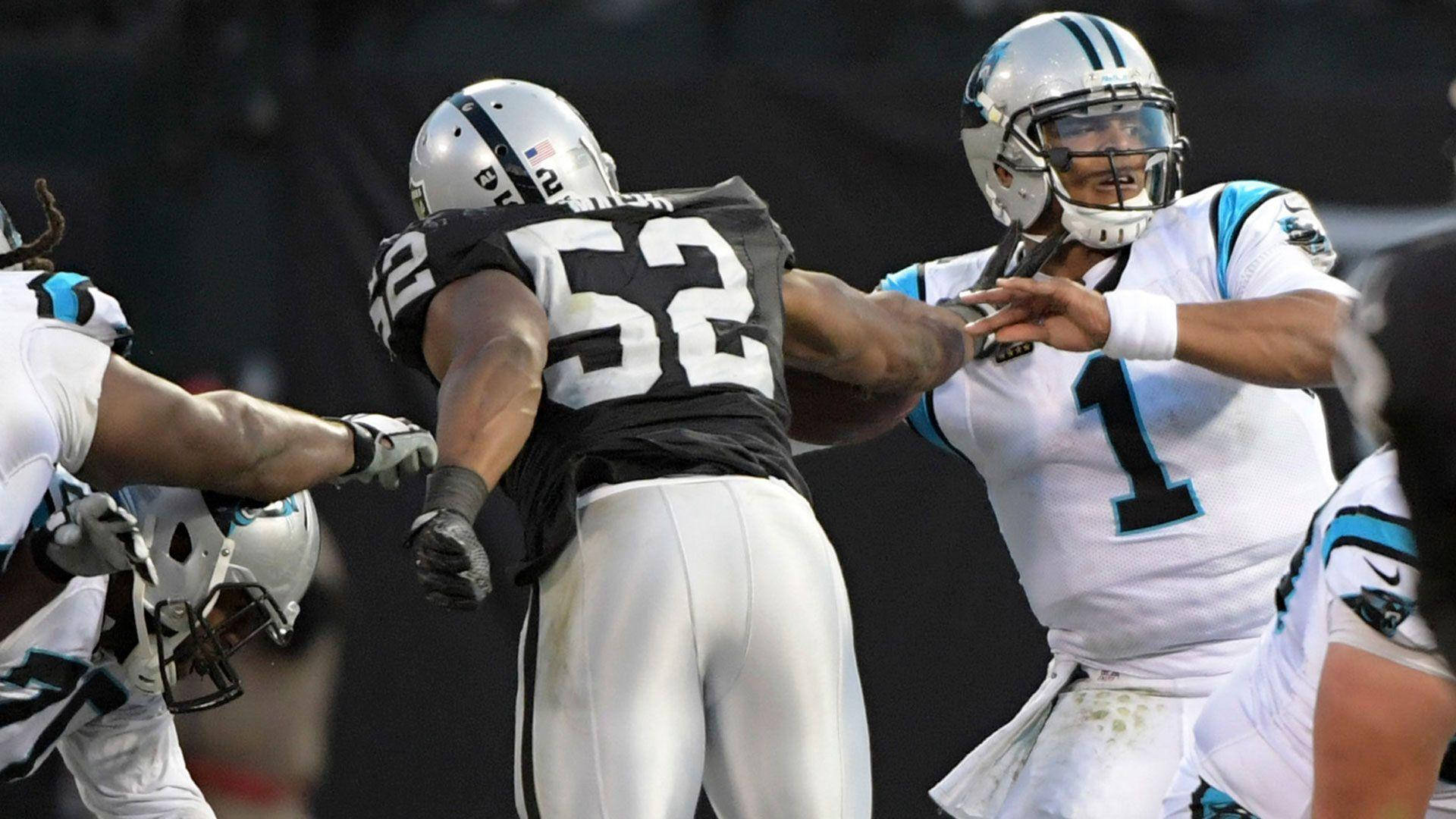 NFL 奧克蘭突襲者隊52號卡里爾·麥克 壁紙 — 一名身穿白色球衣1號的美式足球四分衛在夜間比賽中被身穿黑色球衣52號的線衛擒抱。