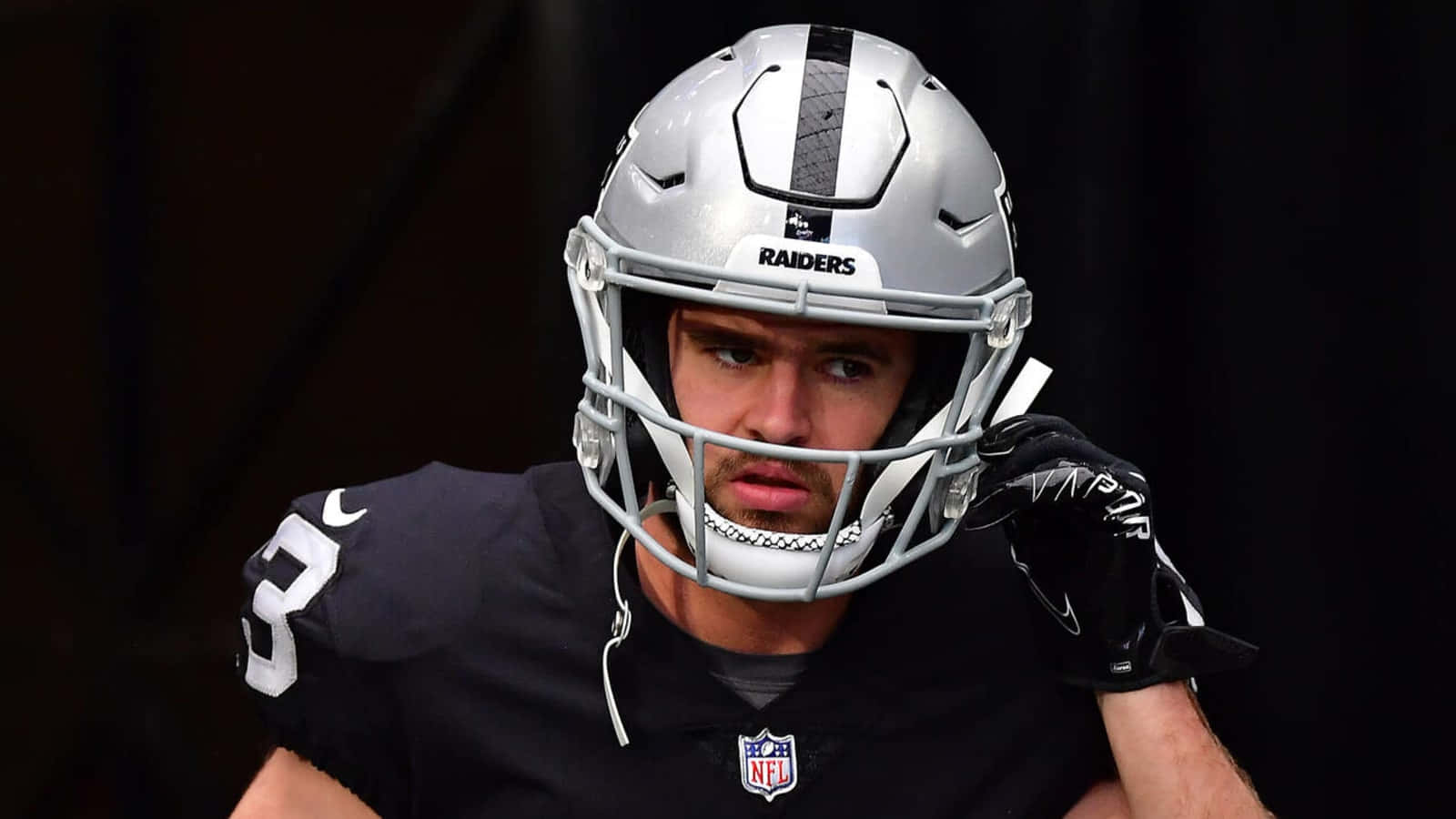 掠奪者 桌布 壁紙 — NFL 美式足球員戴上 Raiders 頭盔和球衣，近距離凝視鏡頭。