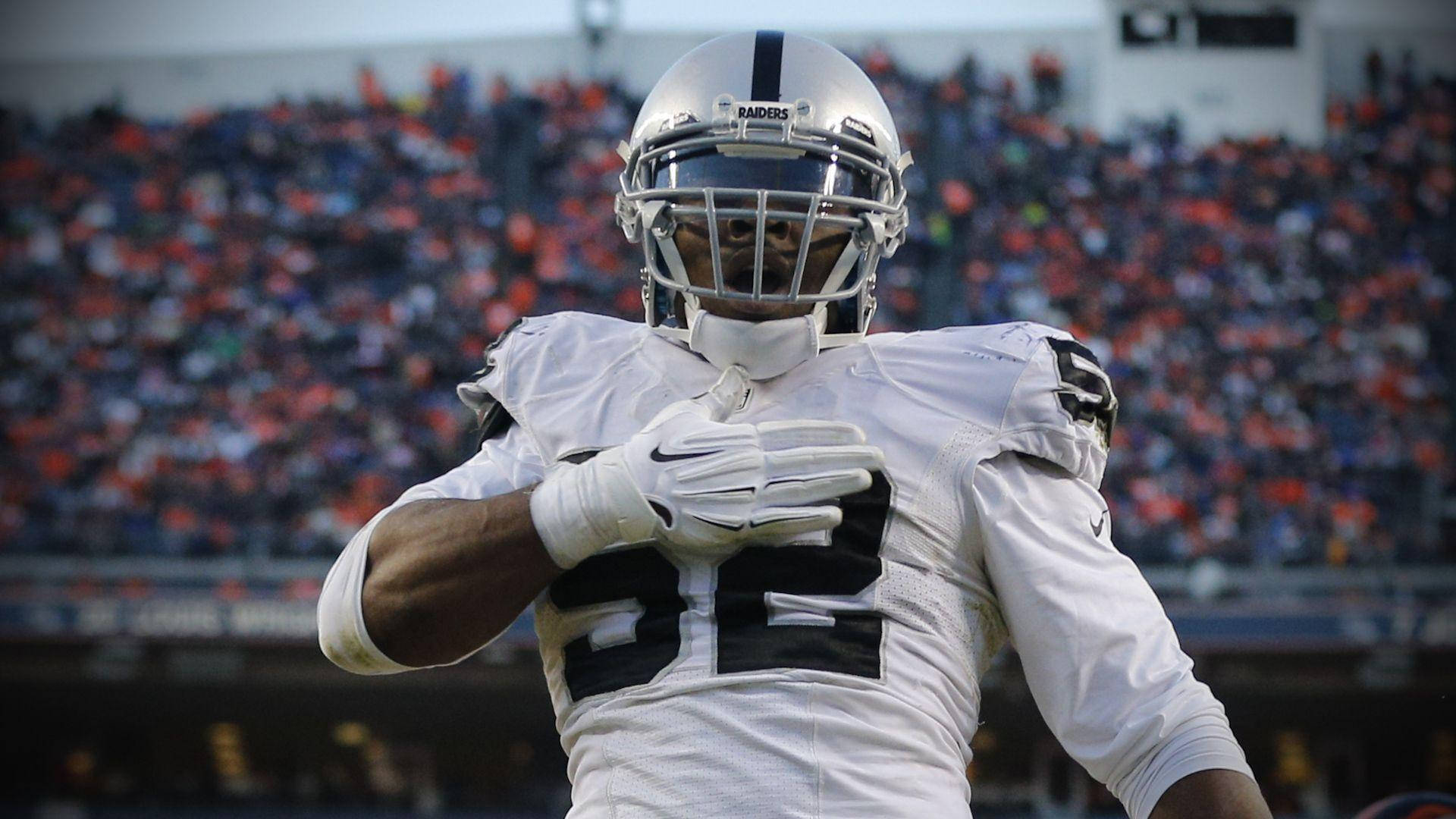 NFL 芝加哥熊隊卡里爾·麥克52號 壁紙 — 一名身穿白色Raiders球衣、號碼22的美式足球選手在模糊的體育場人群前慶祝。