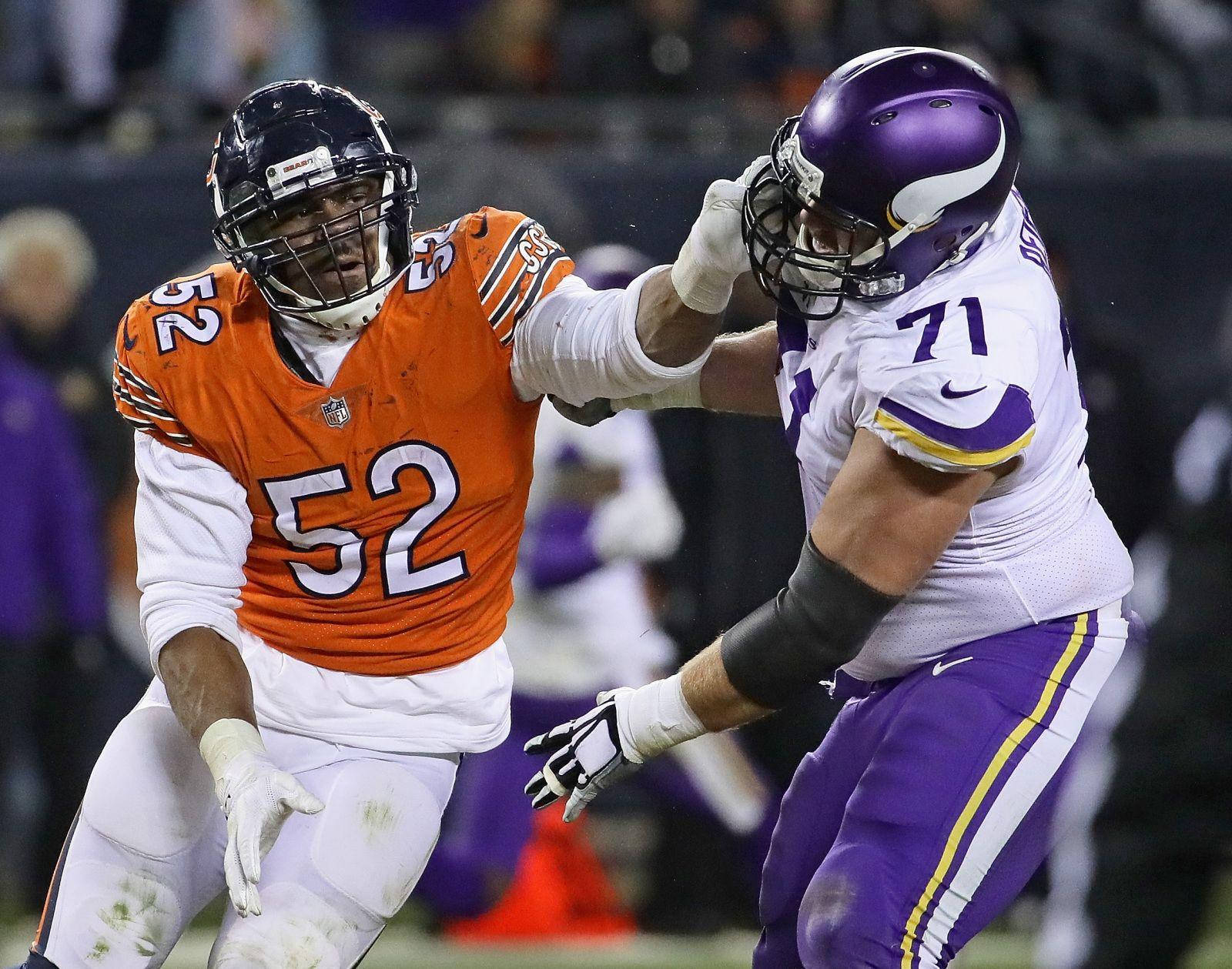 NFL 芝加哥熊隊卡里爾·麥克對戰紐約巨人隊 壁紙 — 兩名身穿橙色和紫色球衣的NFL球員在夜間比賽中於球場燈光下激烈纏鬥。