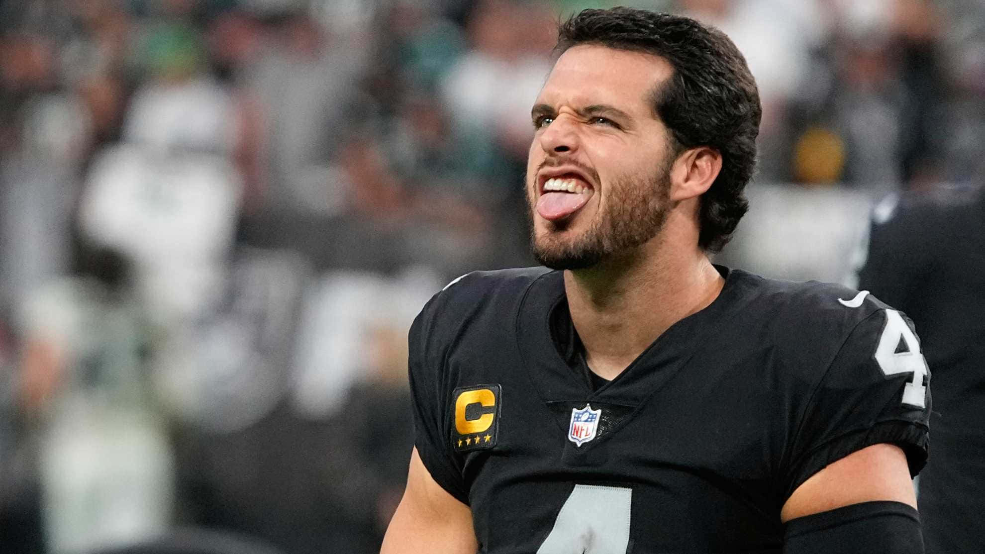 掠奪者 桌布 壁紙 — NFL四分衛在比賽中伸出舌頭，表情專注，身穿黑色球衣，號碼4，帶有隊長臂章。