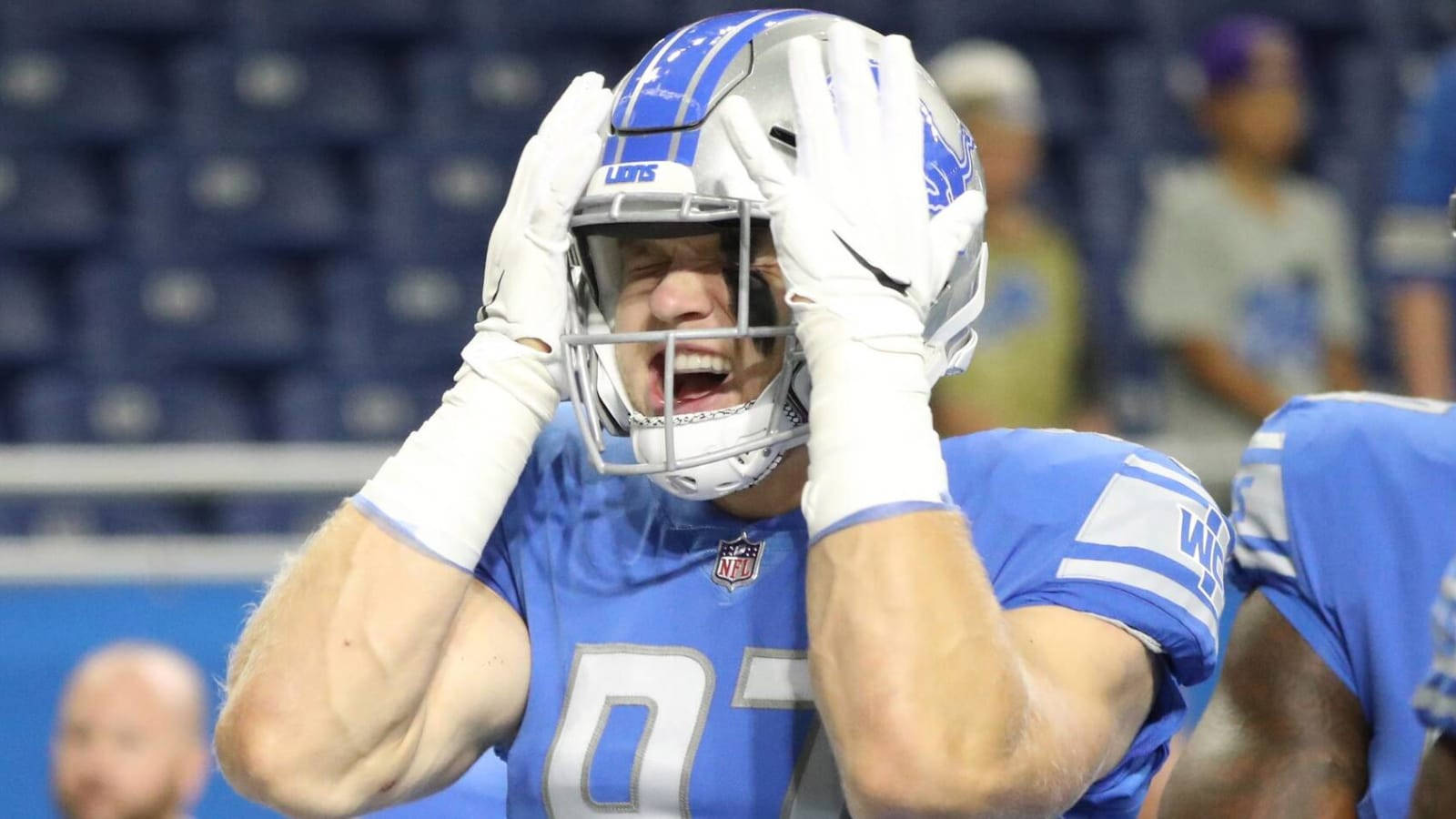 NFL底特律獵鷹隊對西雅圖海鷹隊艾丹·哈欽遜的搞笑瞬間 壁紙 — 底特律獅子隊的藍色制服美式足球員在球場燈光下比賽時，雙手放在頭盔上尖叫。