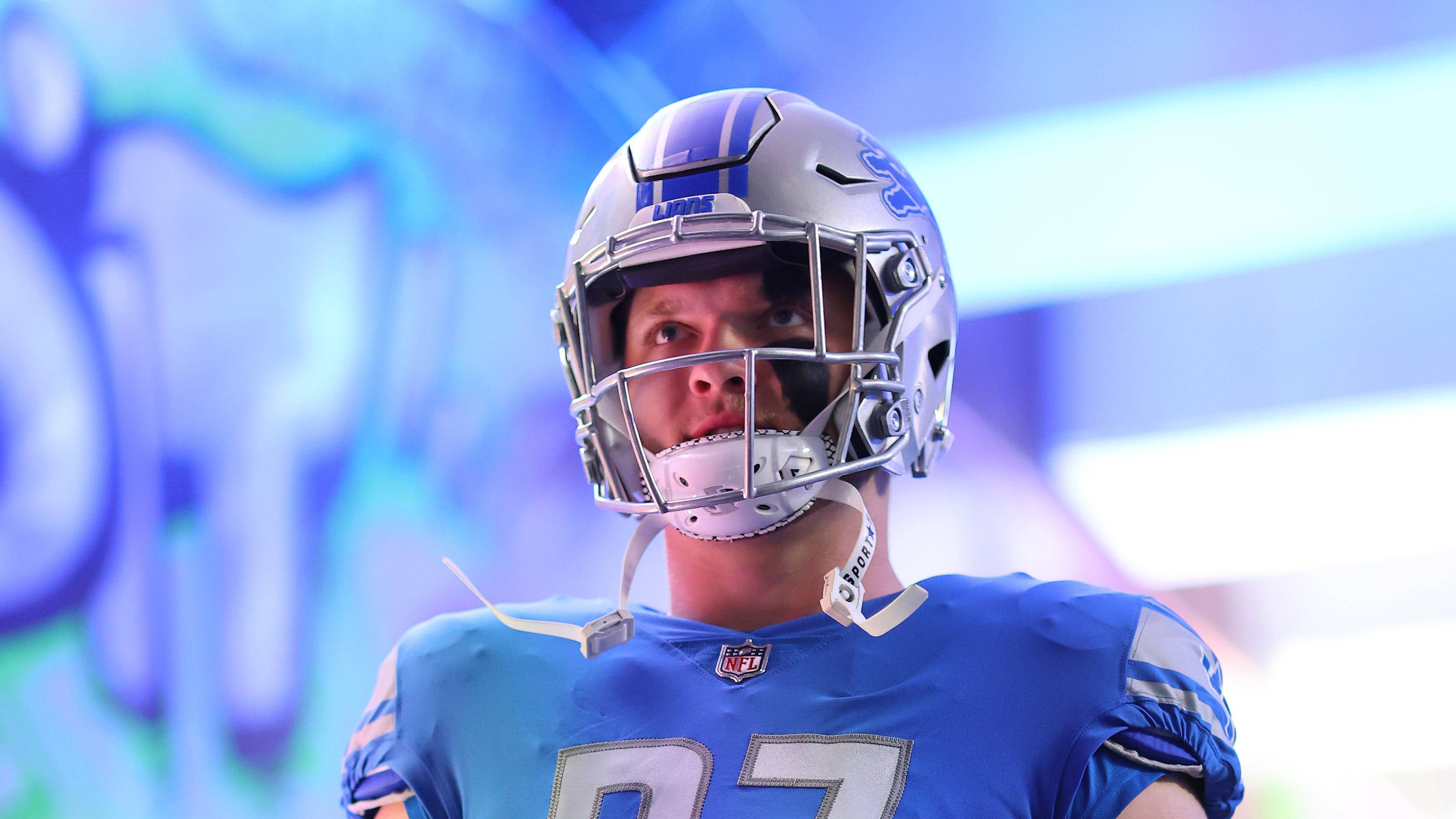NFL底特律獵鷹隊防守端鋒艾丹·漢遜 壁紙 — 底特律雄獅美式足球員的近距離特寫，身穿藍色球衣和銀色頭盔，目光專注地向前看。