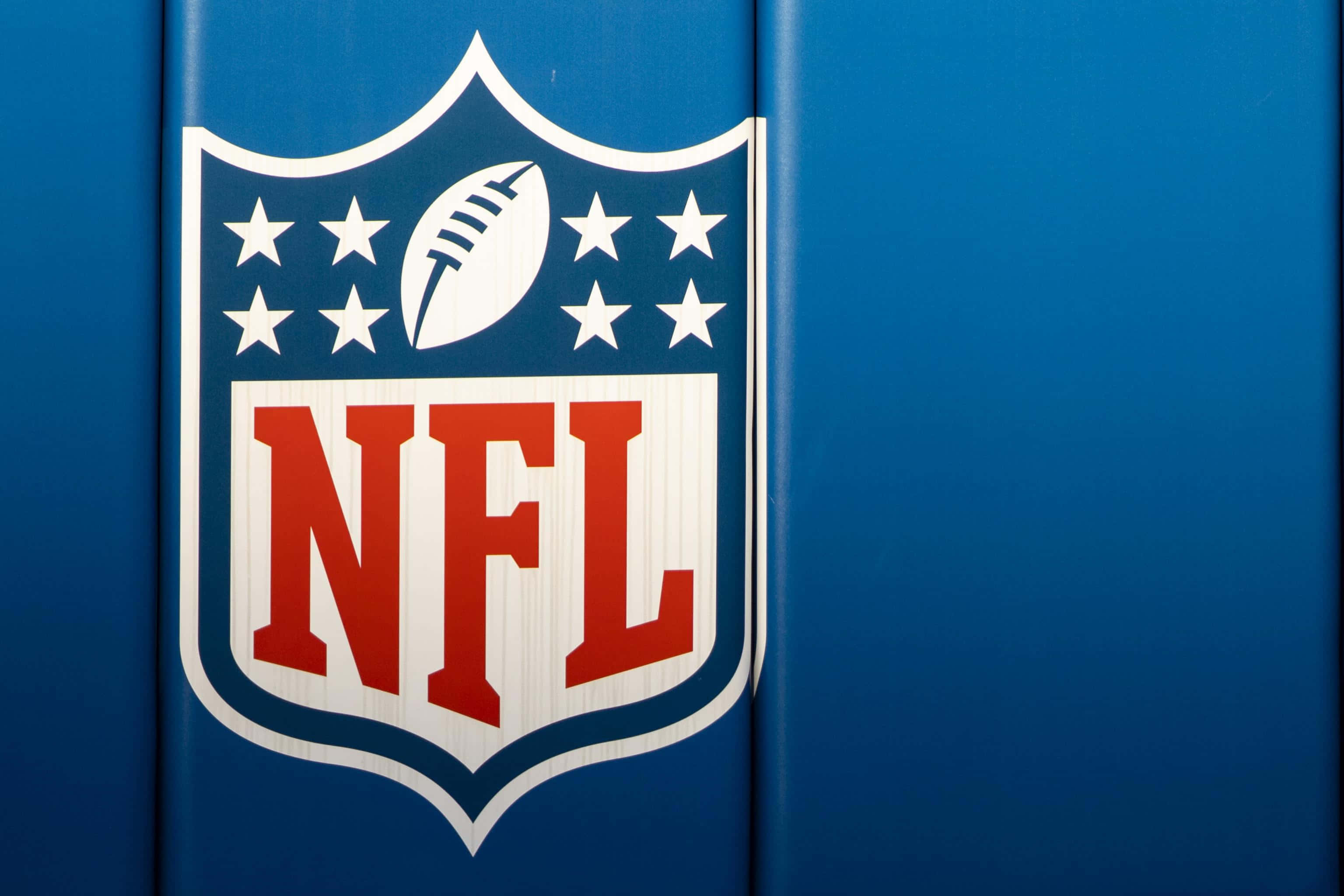 NFL Logo 桌布 壁紙 — NFL標誌特寫，帶有白色星星和足球，背景為藍色。