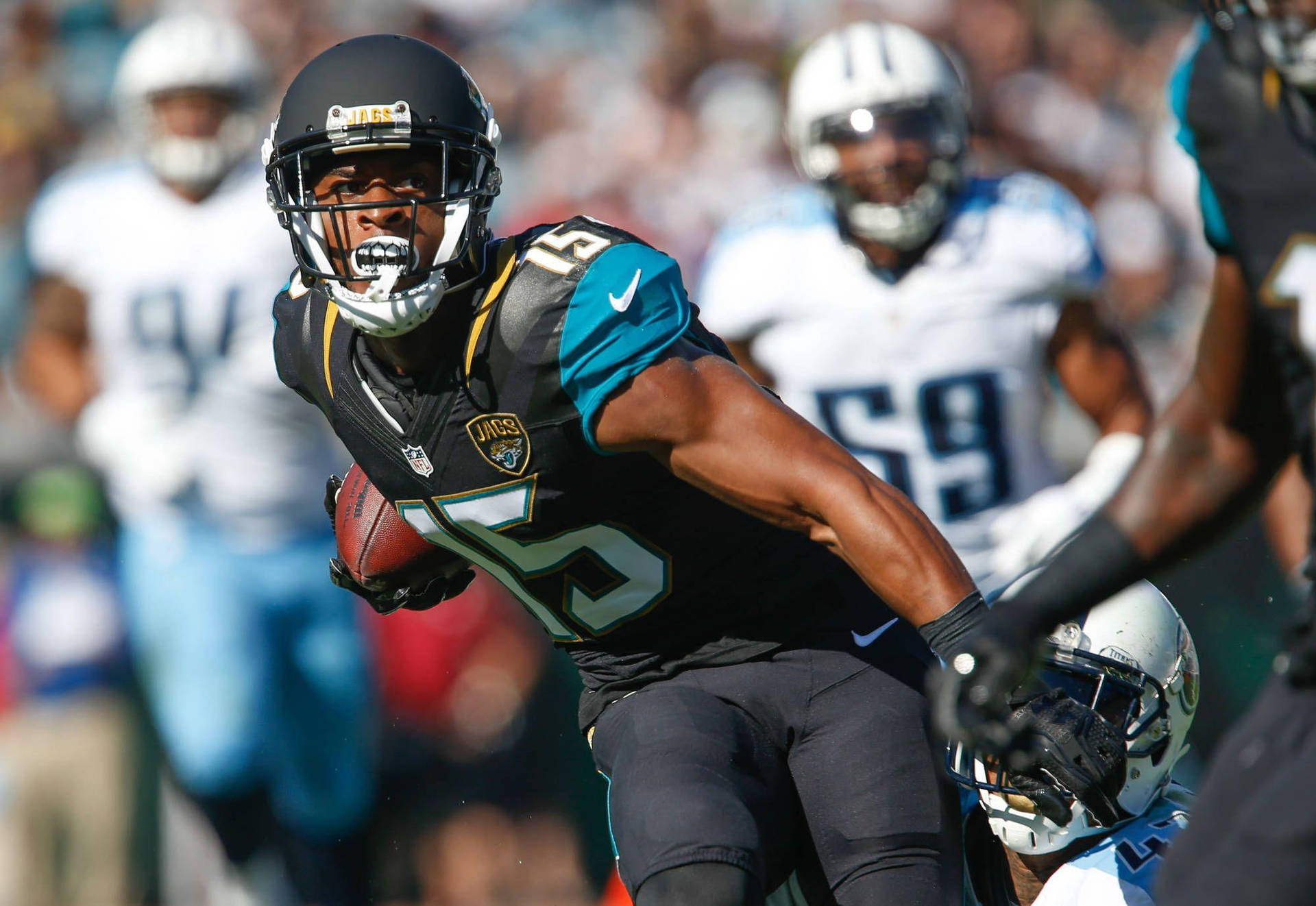 NFL比賽15號艾倫·羅賓遜 壁紙 — 一名身穿黑色和青綠色球衣的傑克遜維爾美洲虎隊美式足球員，在日間比賽中持球衝刺，對手模糊不清。