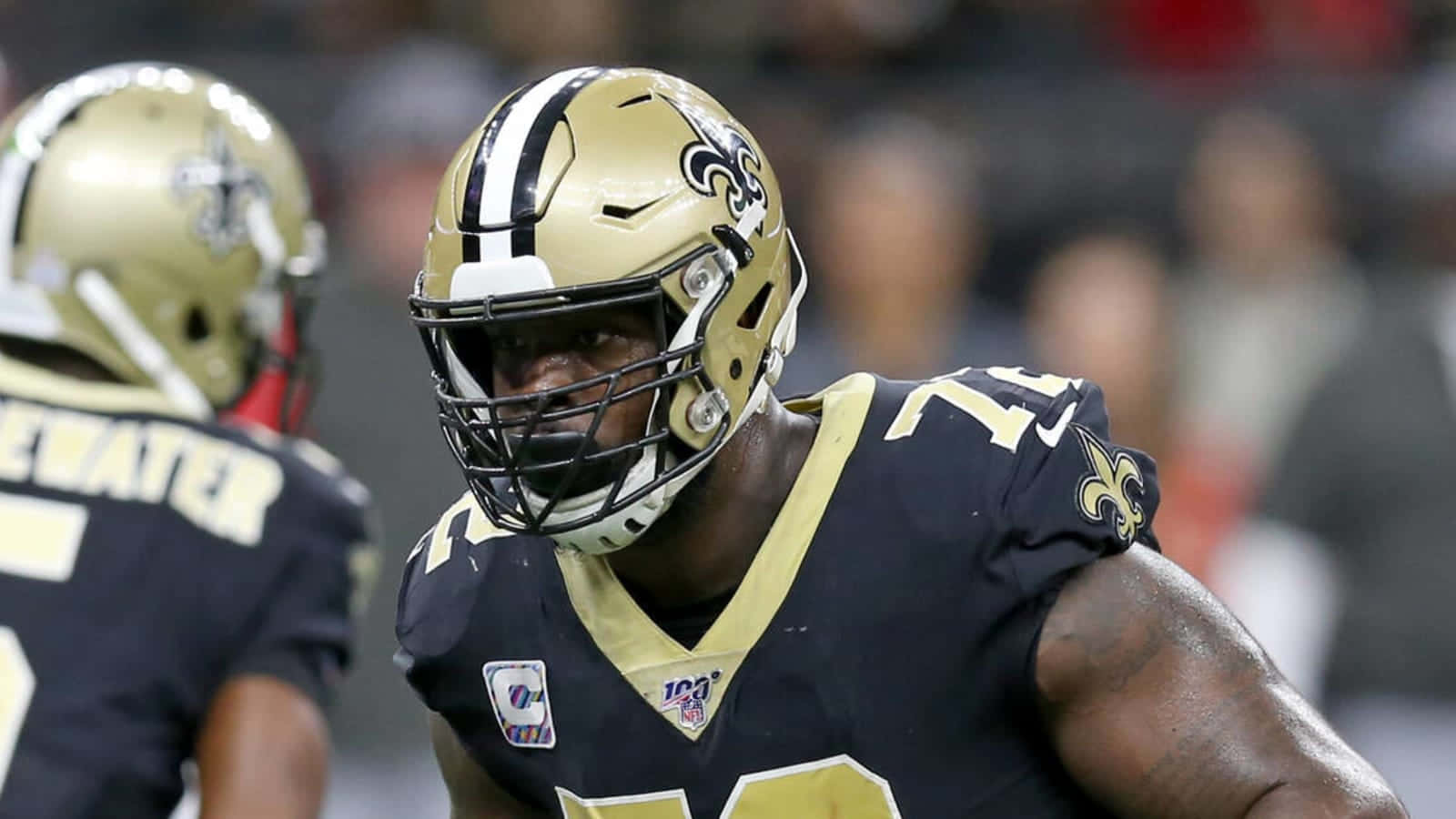 NFL球員 特龍·阿姆斯特德 美式足球 壁紙 — 新奧爾良聖徒隊美式足球員身穿金色和黑色裝備，在比賽中高度集中的特寫。