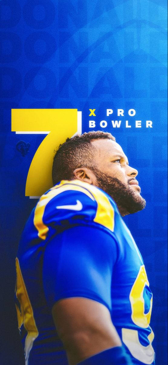 NFL球員亞倫·唐納德仰望瞬間 壁紙 — 一名身穿藍黃色球衣的足球運動員在搶眼的藍色背景上仰望一個巨大的黃色數字七和文字。