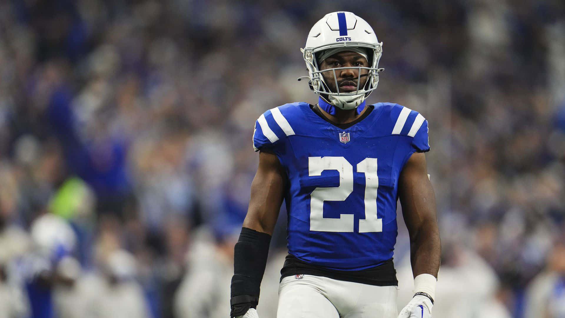 NFL球員扎克·莫斯21號 壁紙 — 一名專注的印第安納波利斯小馬隊美式足球員，身穿藍白球衣背號21，在比賽中站在球場上，身後是模糊的體育場人群。
